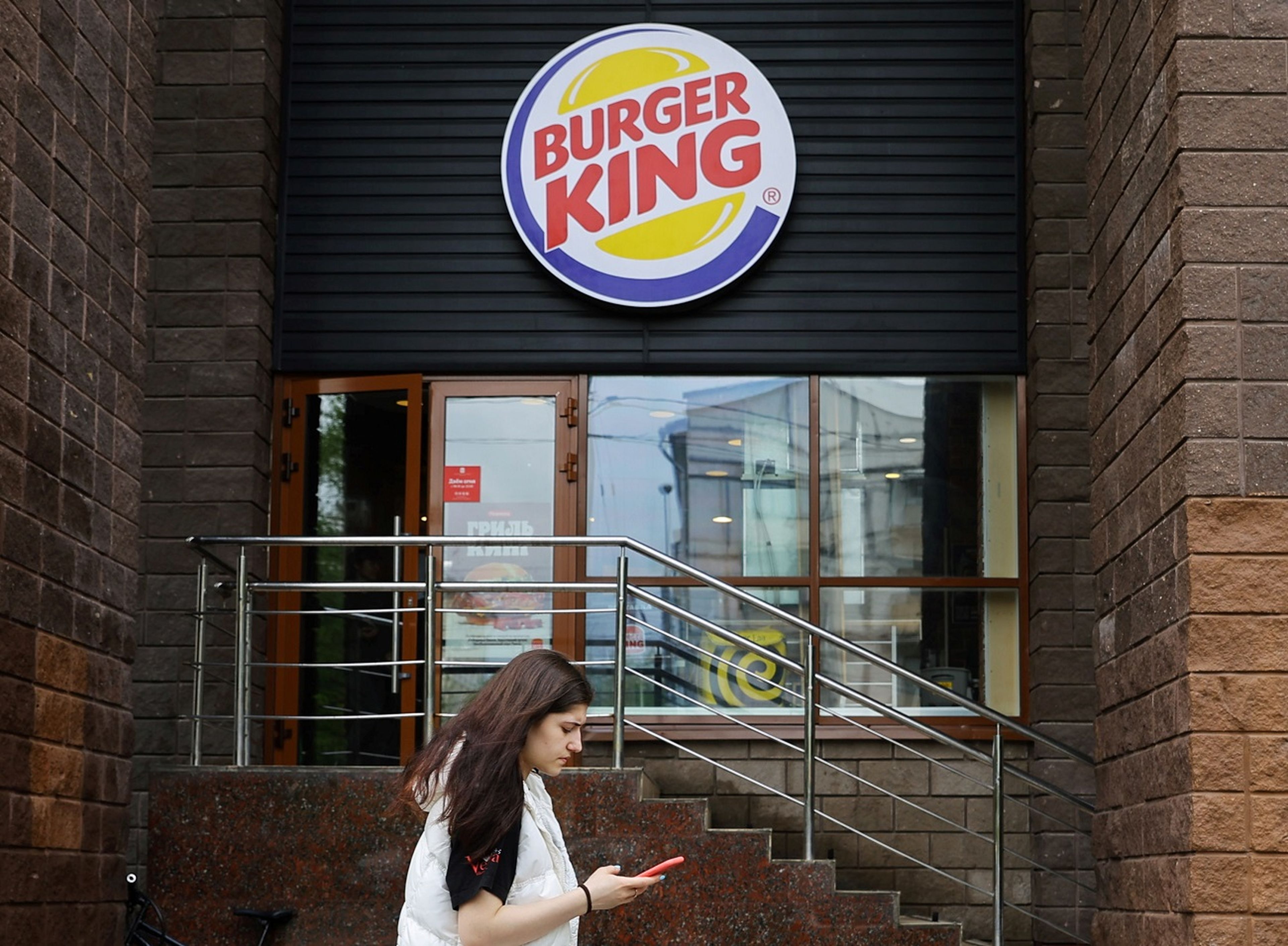 Una chica pasando por delante de la puerta de Burger King.