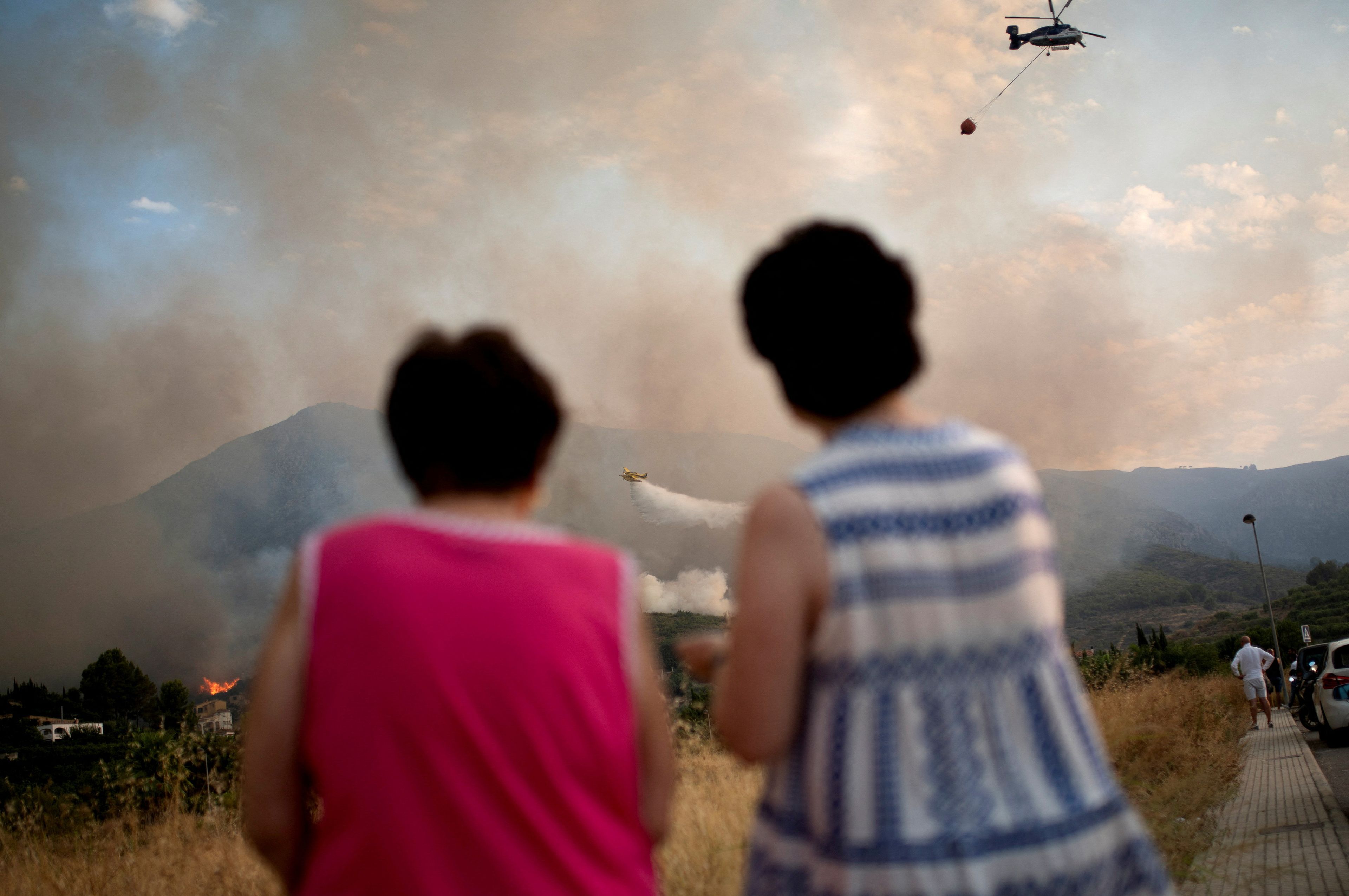 Dos mujeres observan los trabajos para sofocar las llamas cerca de la localidad de Pego