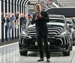 Elon Musk con un Tesla detrás en la fábrica de Gruenheide.
