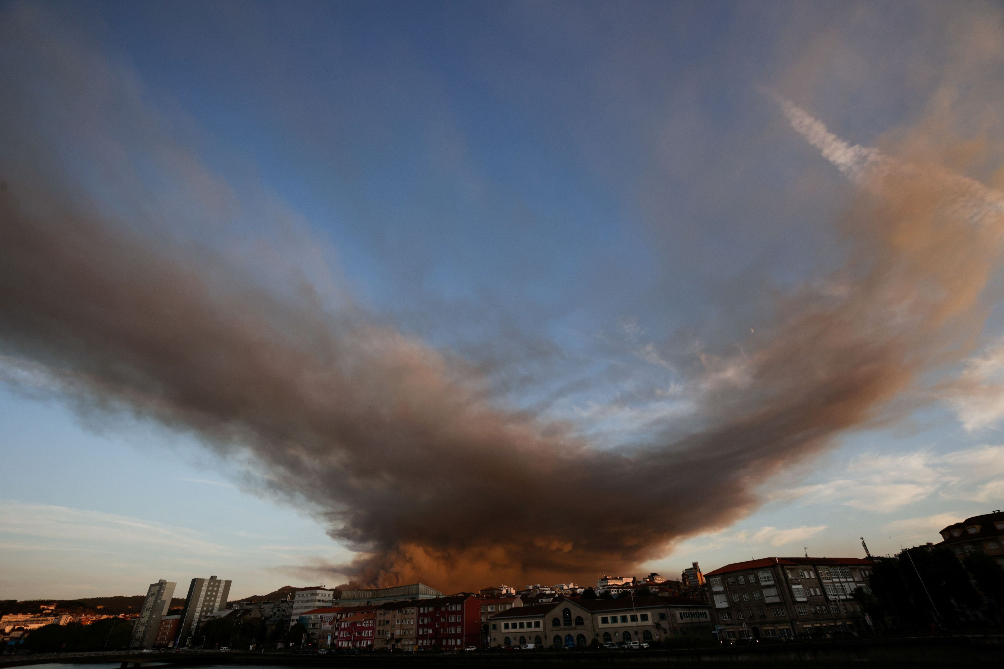 Los fuegos continúan. Siete incendios en Galicia arrasan más de 4.200 hectáreas en menos de una semana y se extienden en Ávila. En la imagen, el humo de un incendio forestal en la montaña de A Fracha se ve desde la ciudad de Pontevedra.