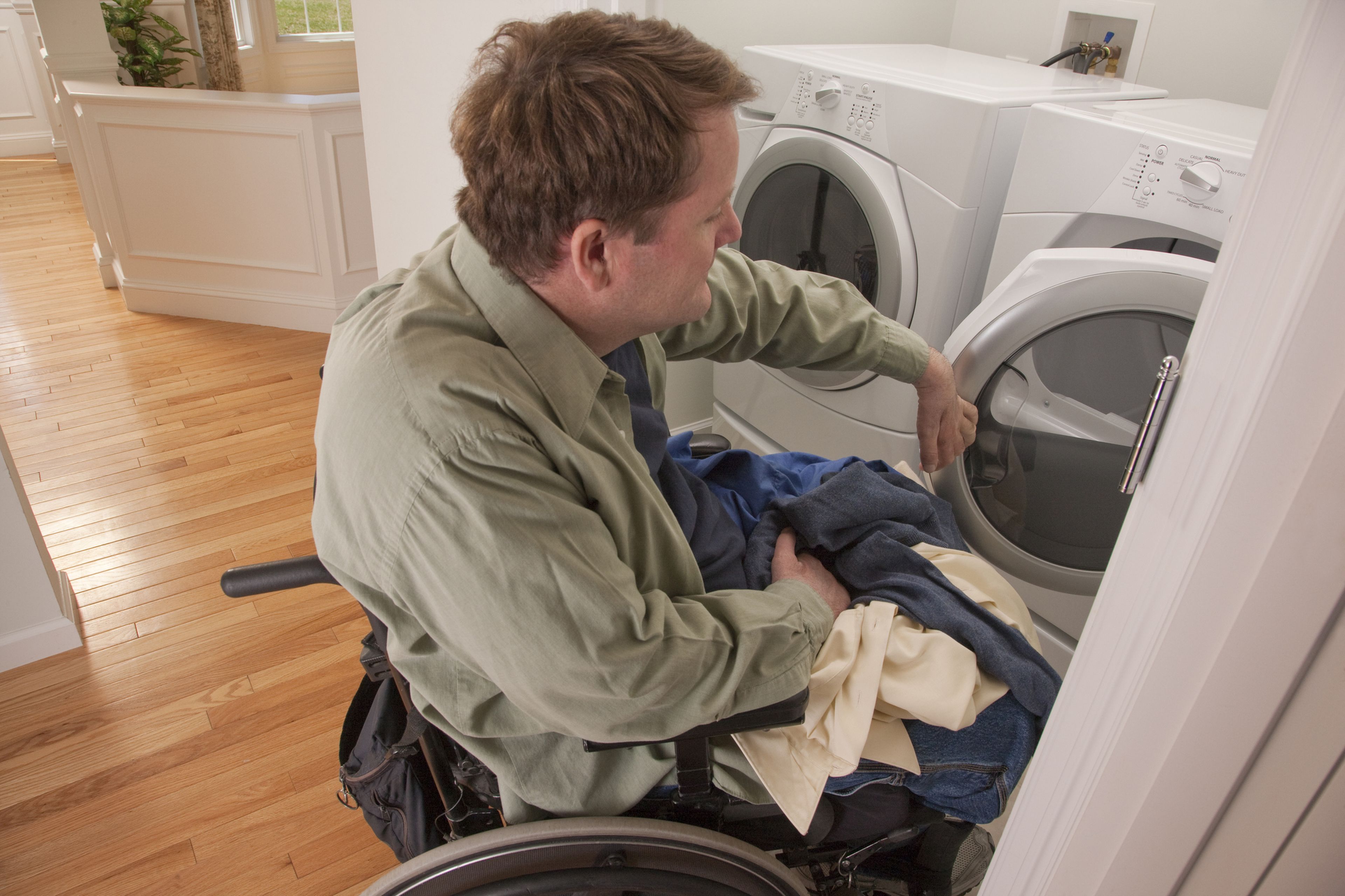 Un hombre en silla de ruedas pone una lavadora.