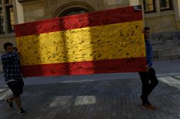 Jóvenes transportan una bandera de España firmada en un acto político.