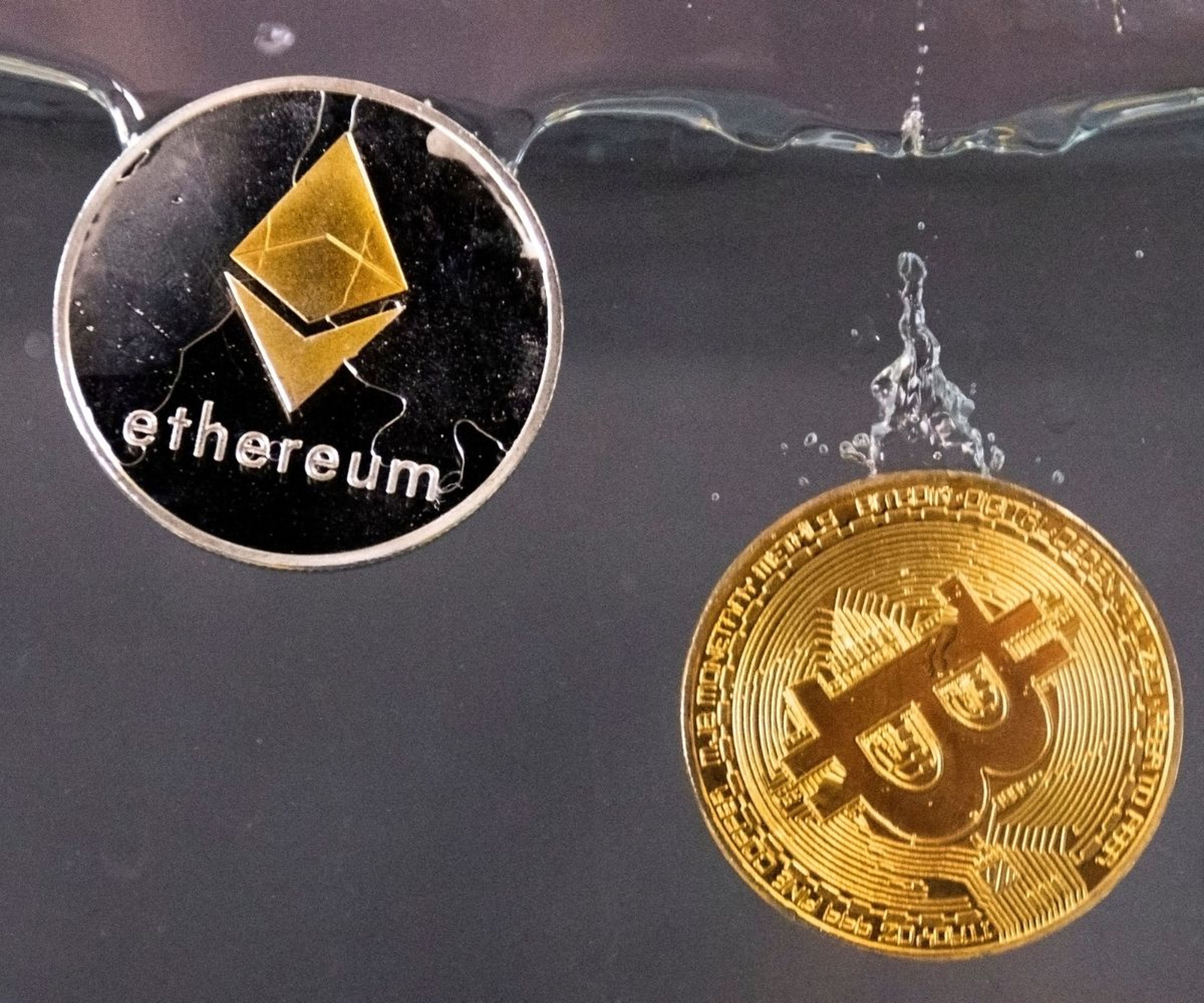 Una moneda de bitcoin y otra de ethereum dentro del agua.