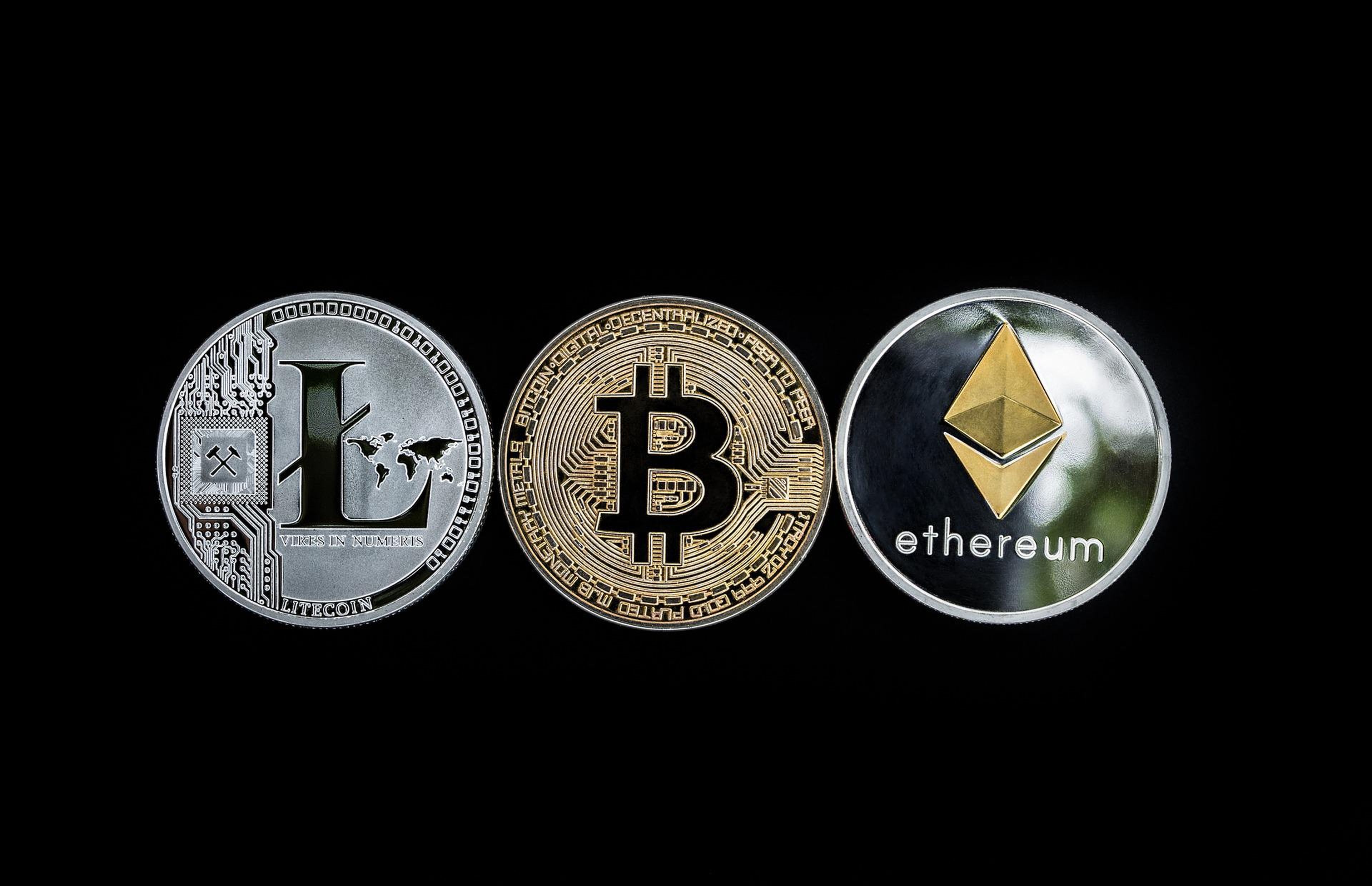 Una moneda de litecoin, otra de bitcoin y otra de ethereum.