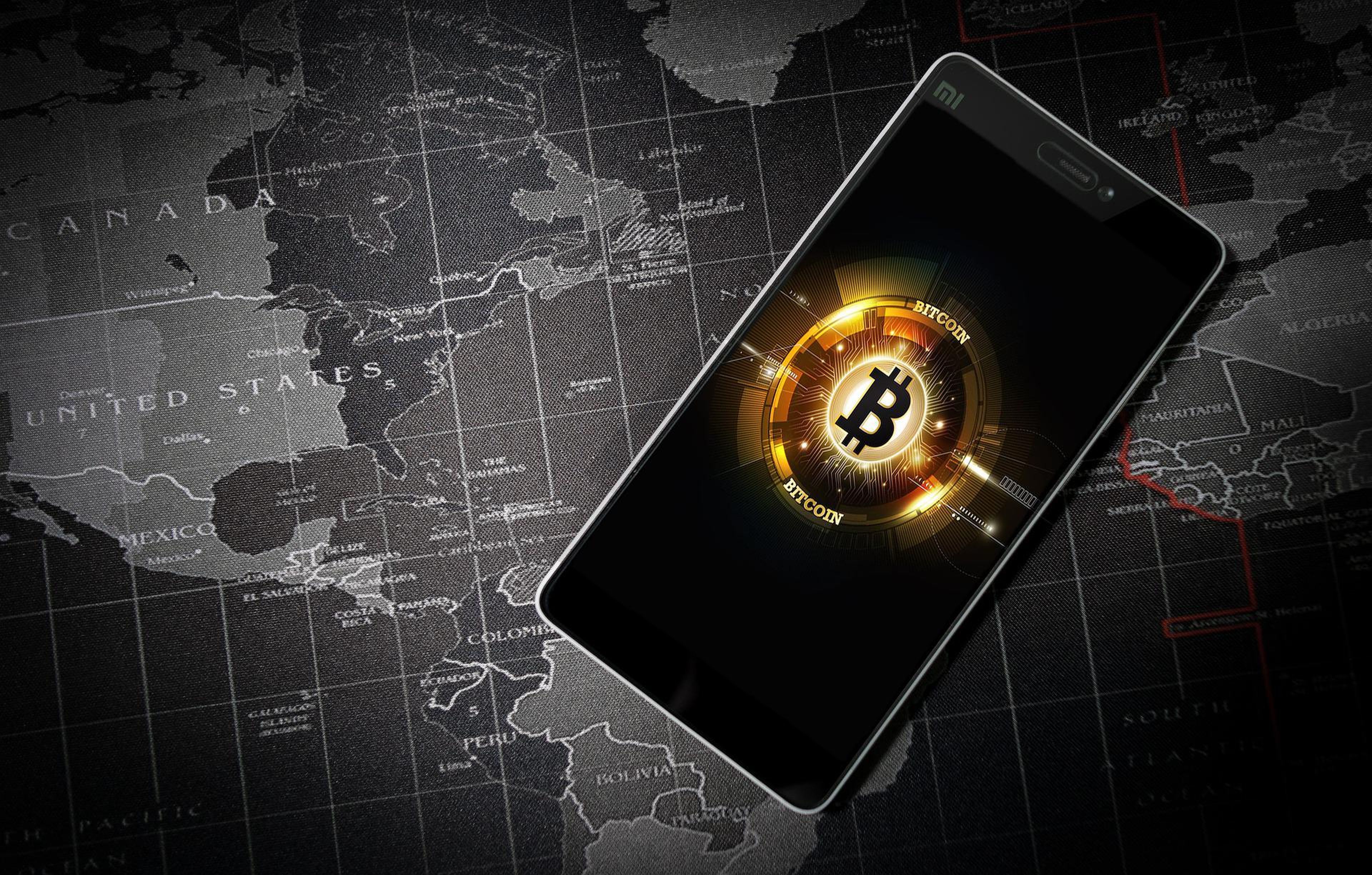 Un móvil, con la imagen de un bitcoin, sobre un mapa.