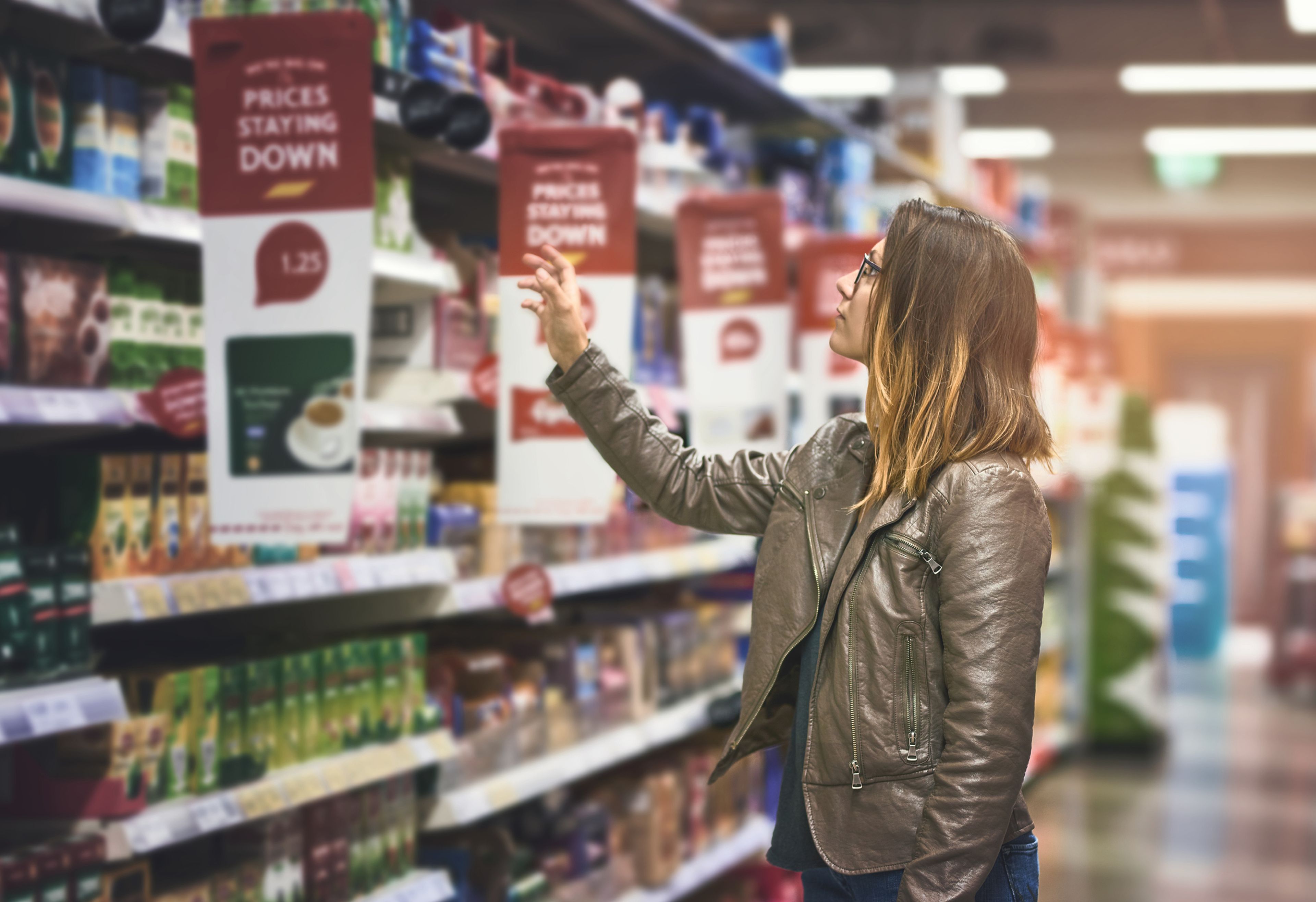 Mujer en el supermercado buscando las marcas blancas más baratas.