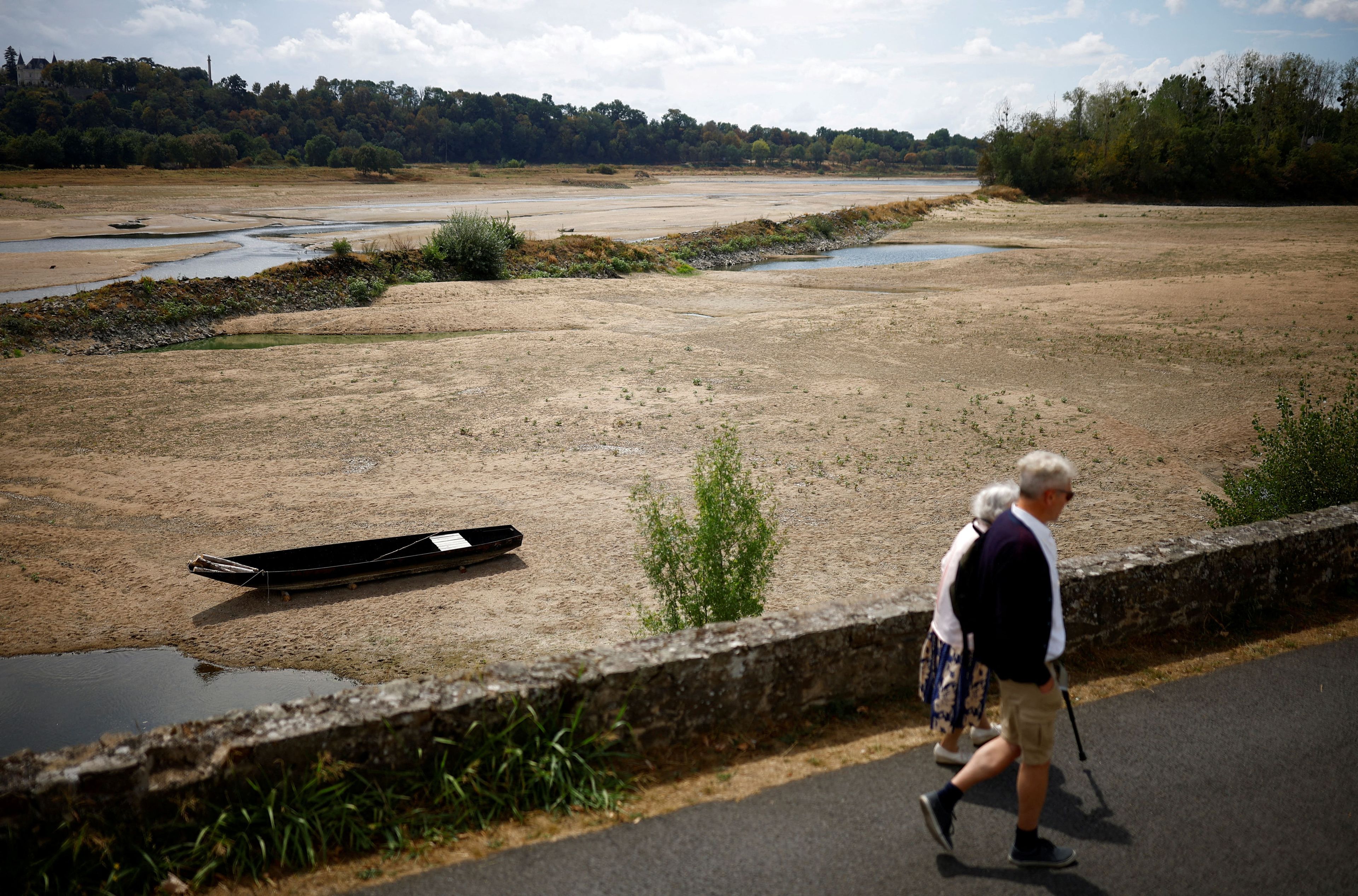 La gente camina cerca de una orilla del río Loira en Loireauxence (Francia), asolado por la sequía, el 16 de agosto de 2022.
