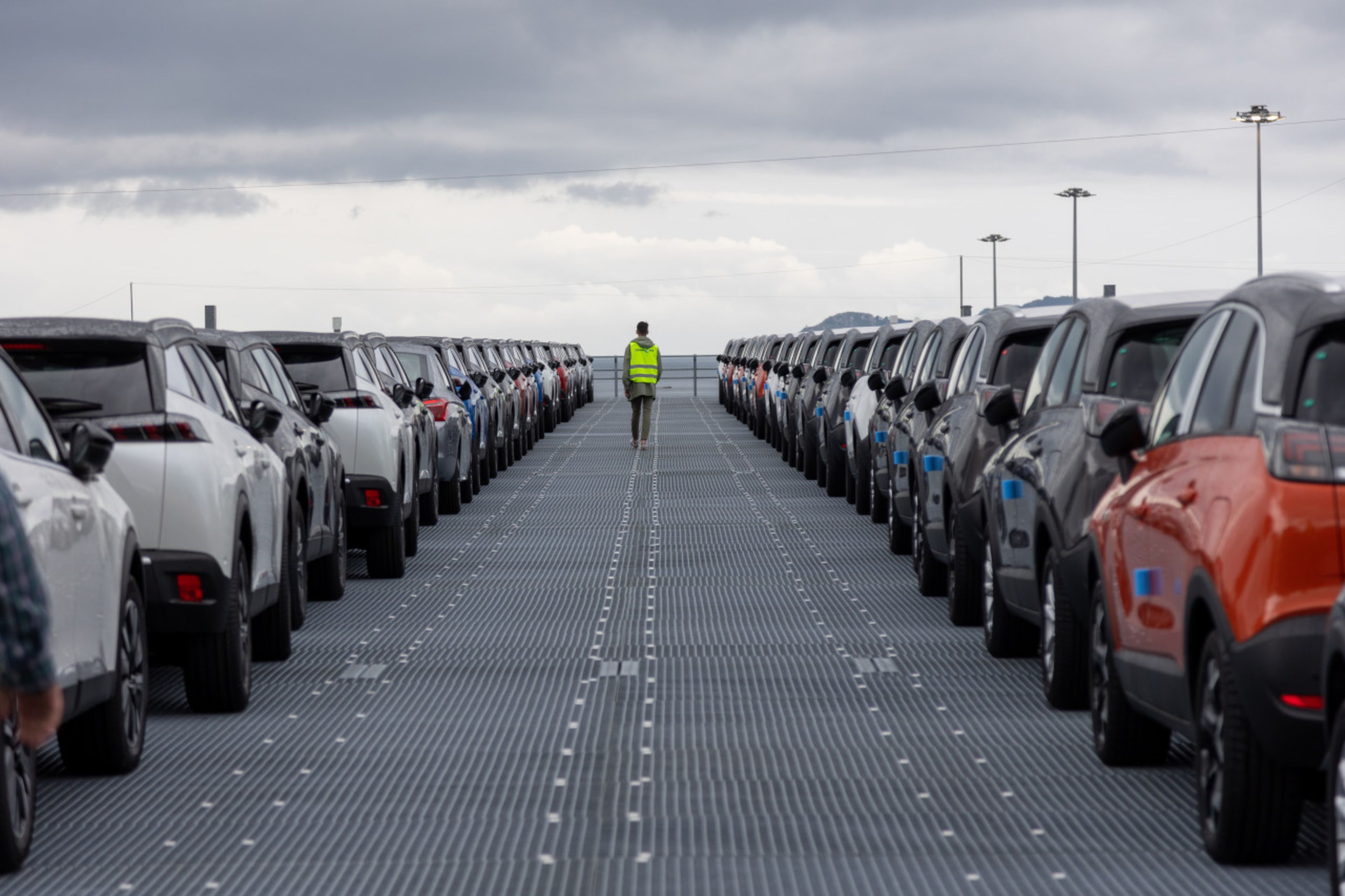Un operario camina entre vehículos de Peugeot y Opel estacionados en los depósitos de la terminal de Bouzas (Vigo)