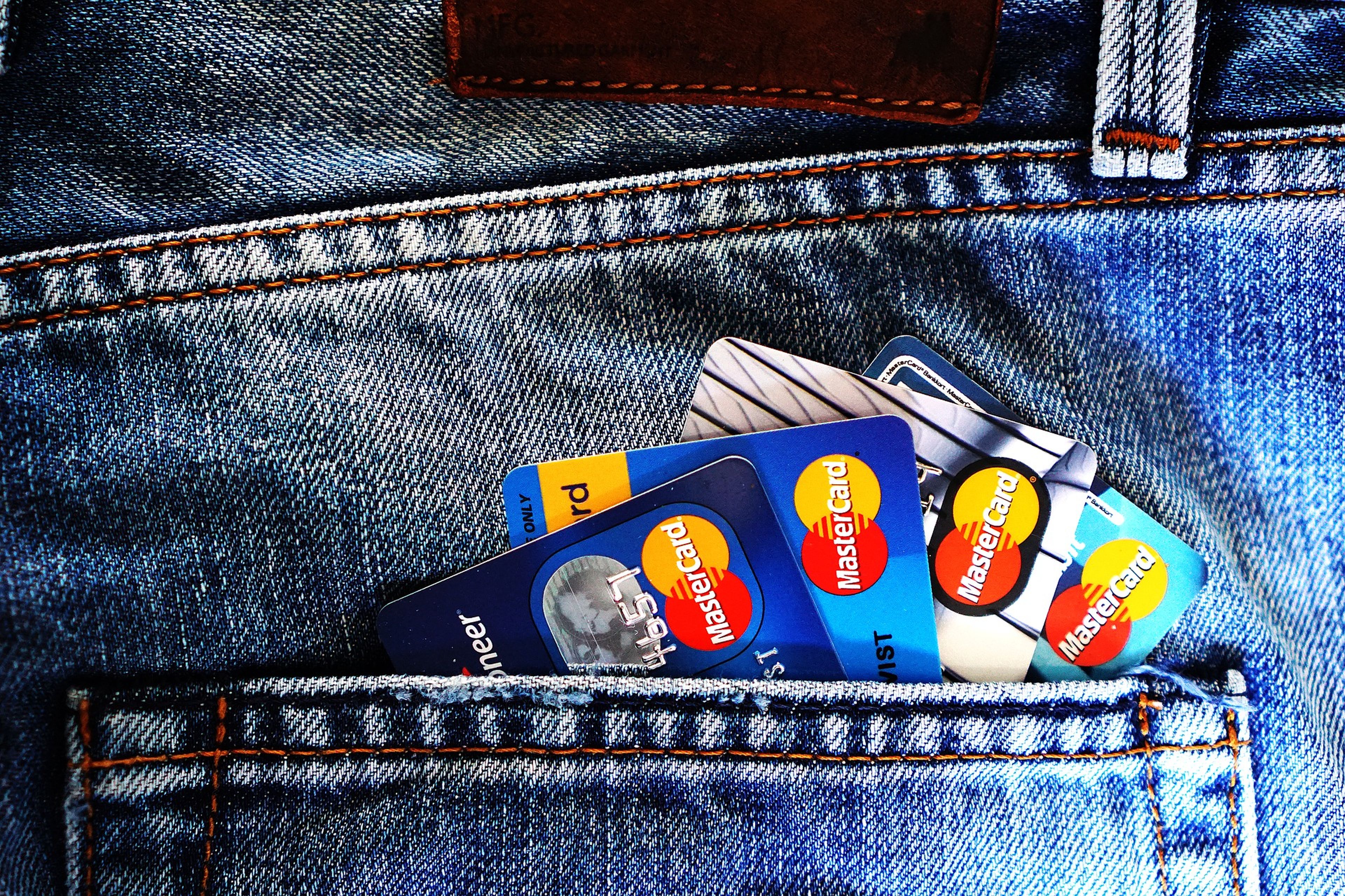 Varias tarjetas de crédito en el bolsillo trasero de unos pantalones vaqueros.