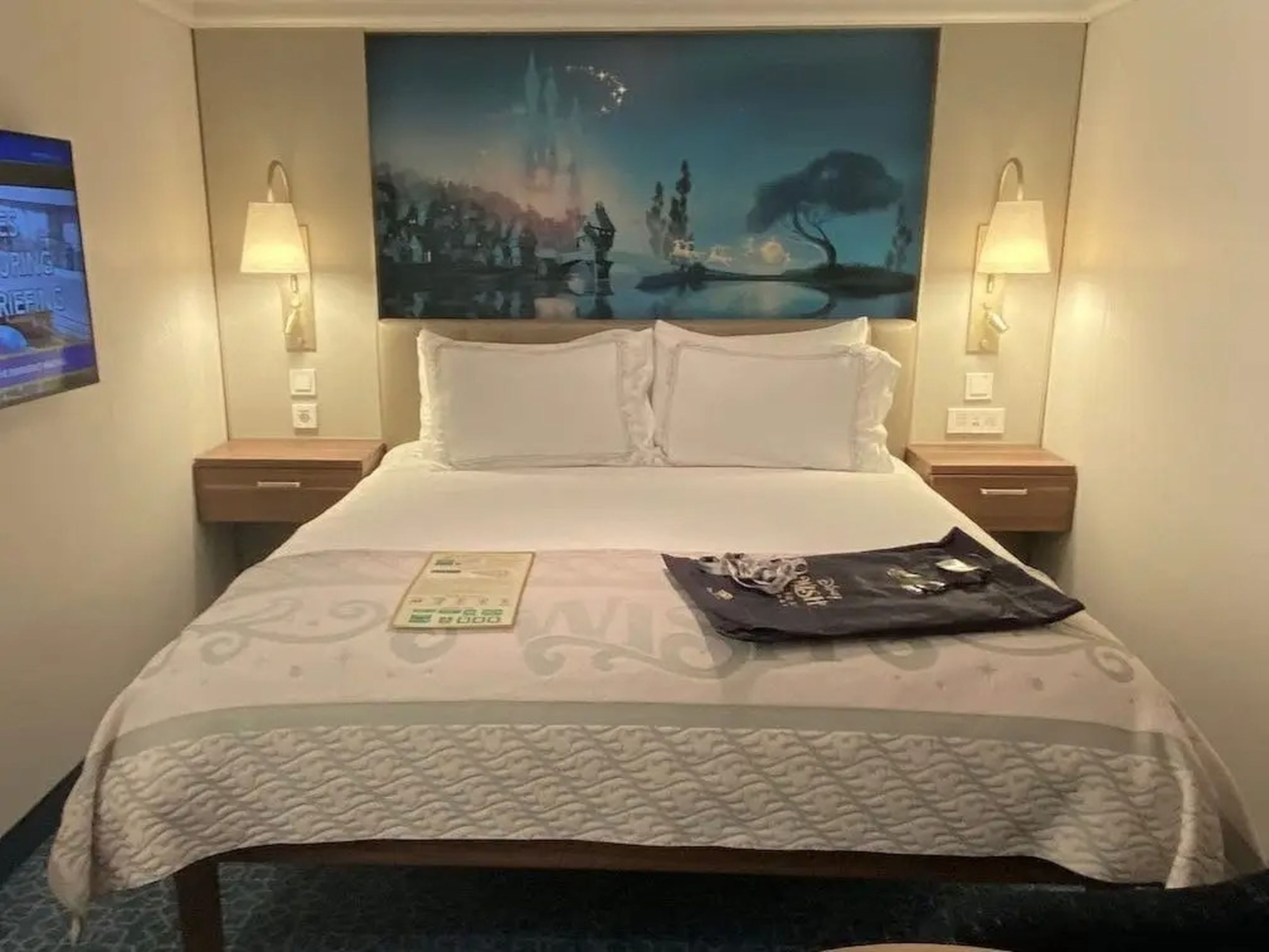 The bed area of a standard stateroom aboard the Disney Wish cruise.