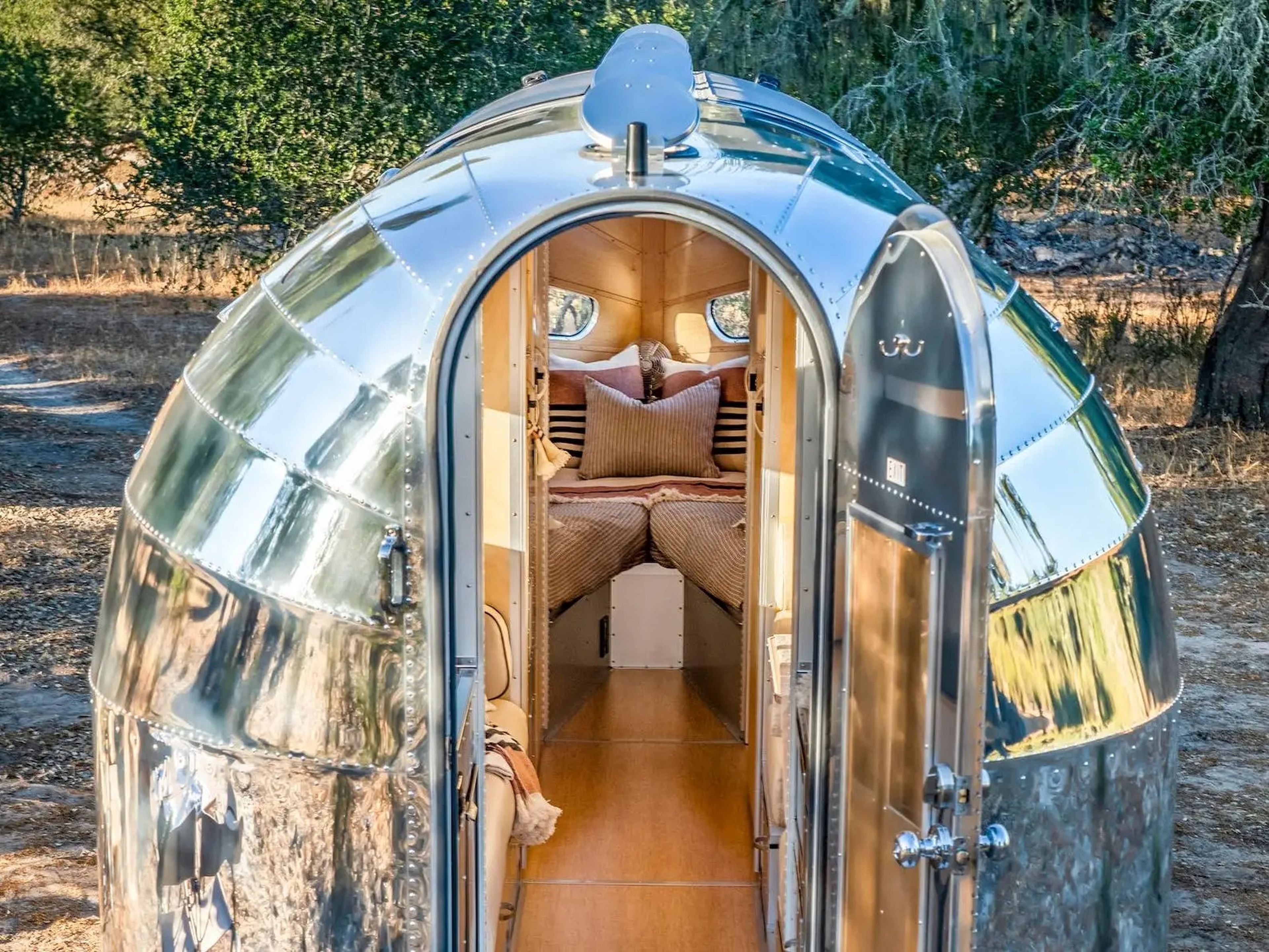 The Bowlus Volterra outside with the rear door open showing the bed.