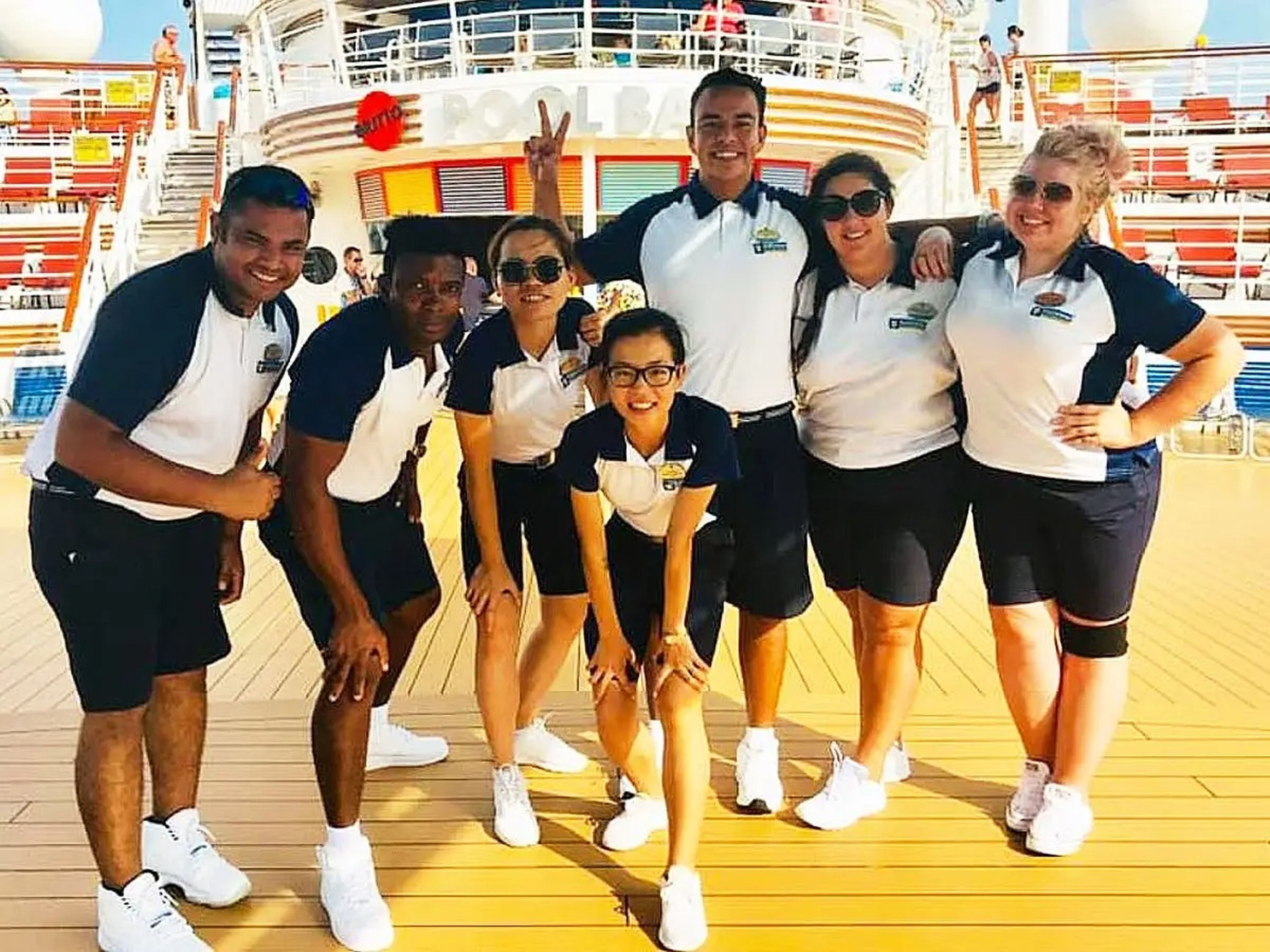 cruise ship staff posing for a photo on the deck of the ship