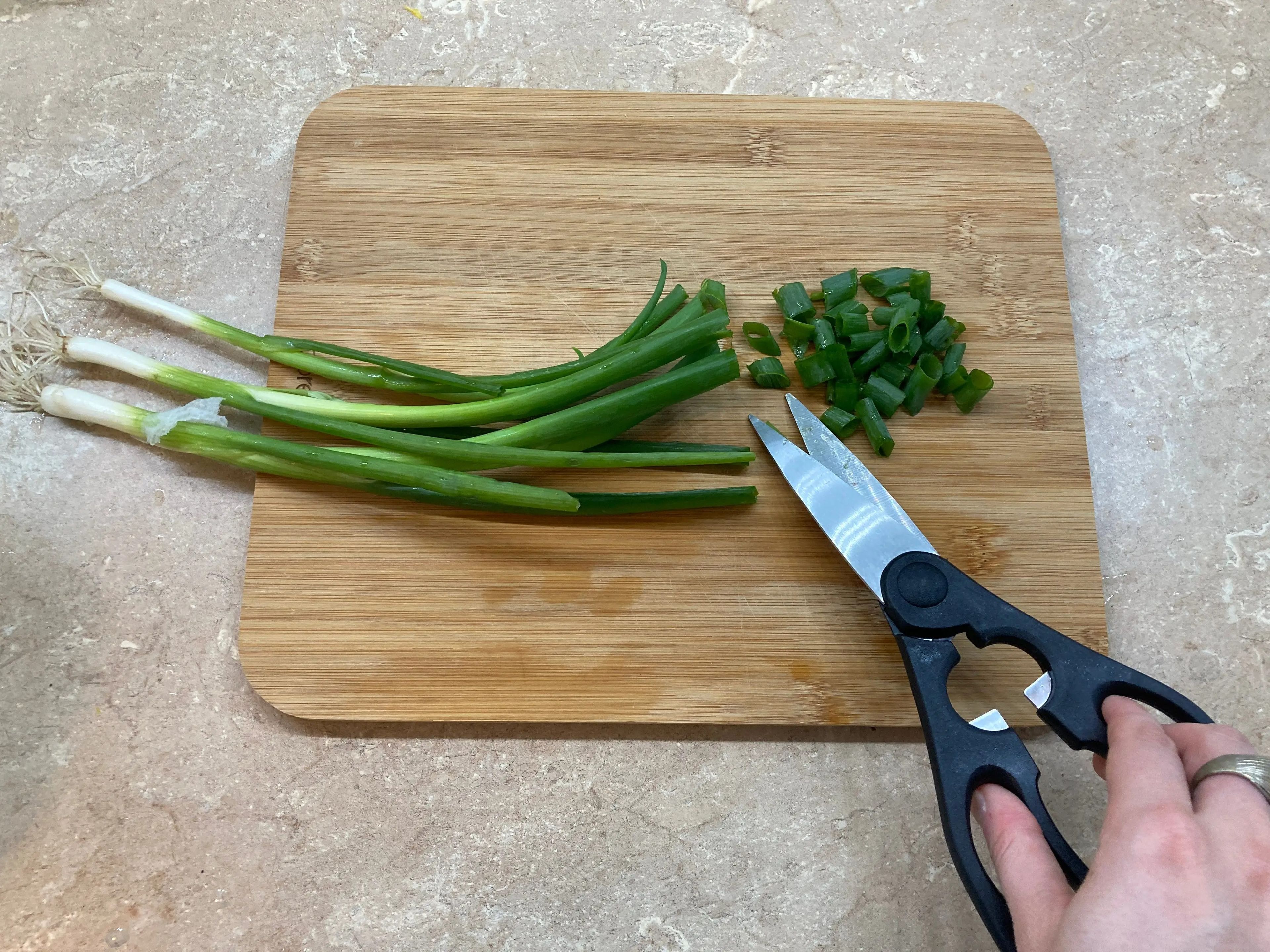 Cortar cebollas verdes con tijeras de cocina.