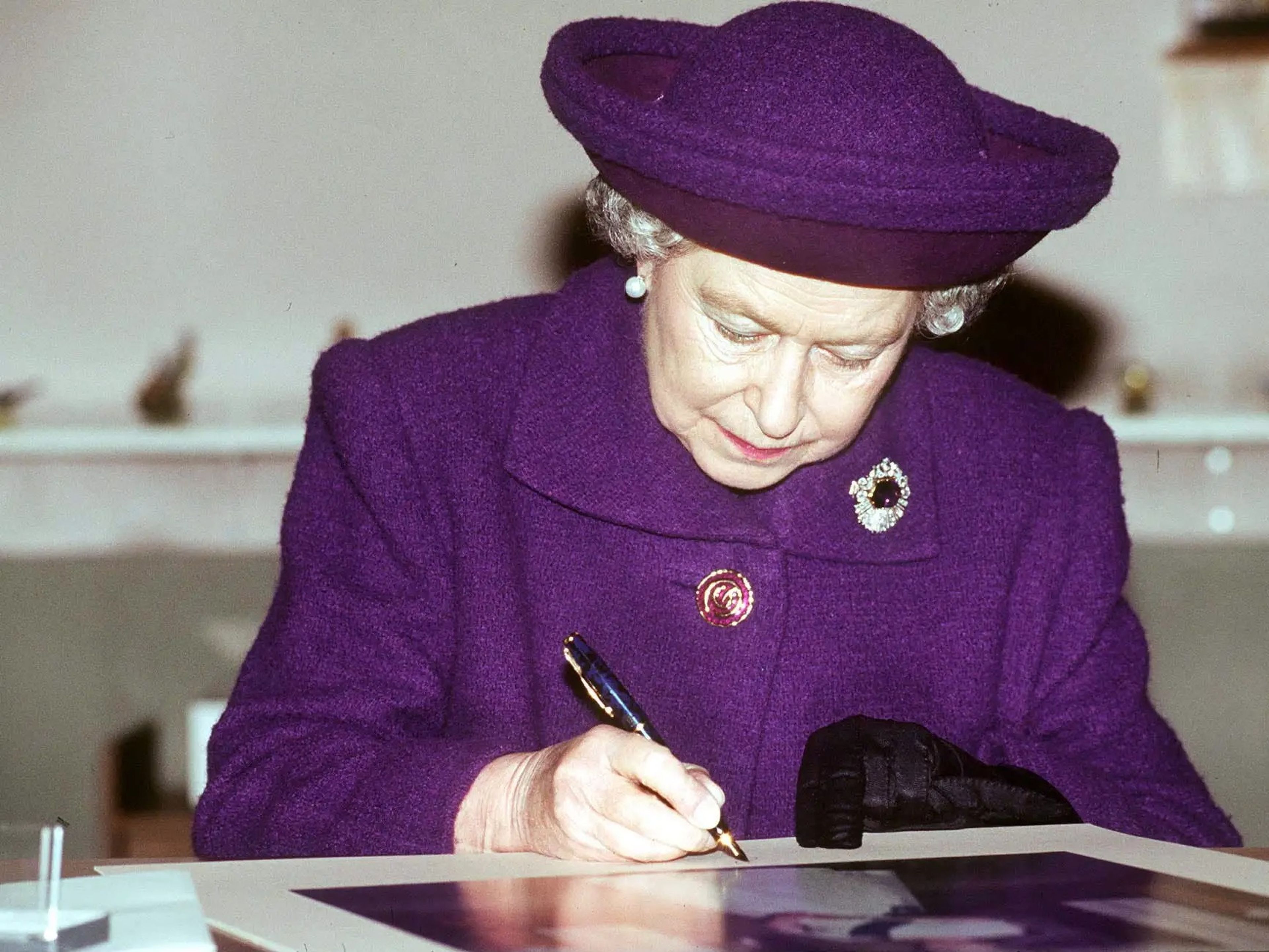 Elizabeth II firmando fotografías.