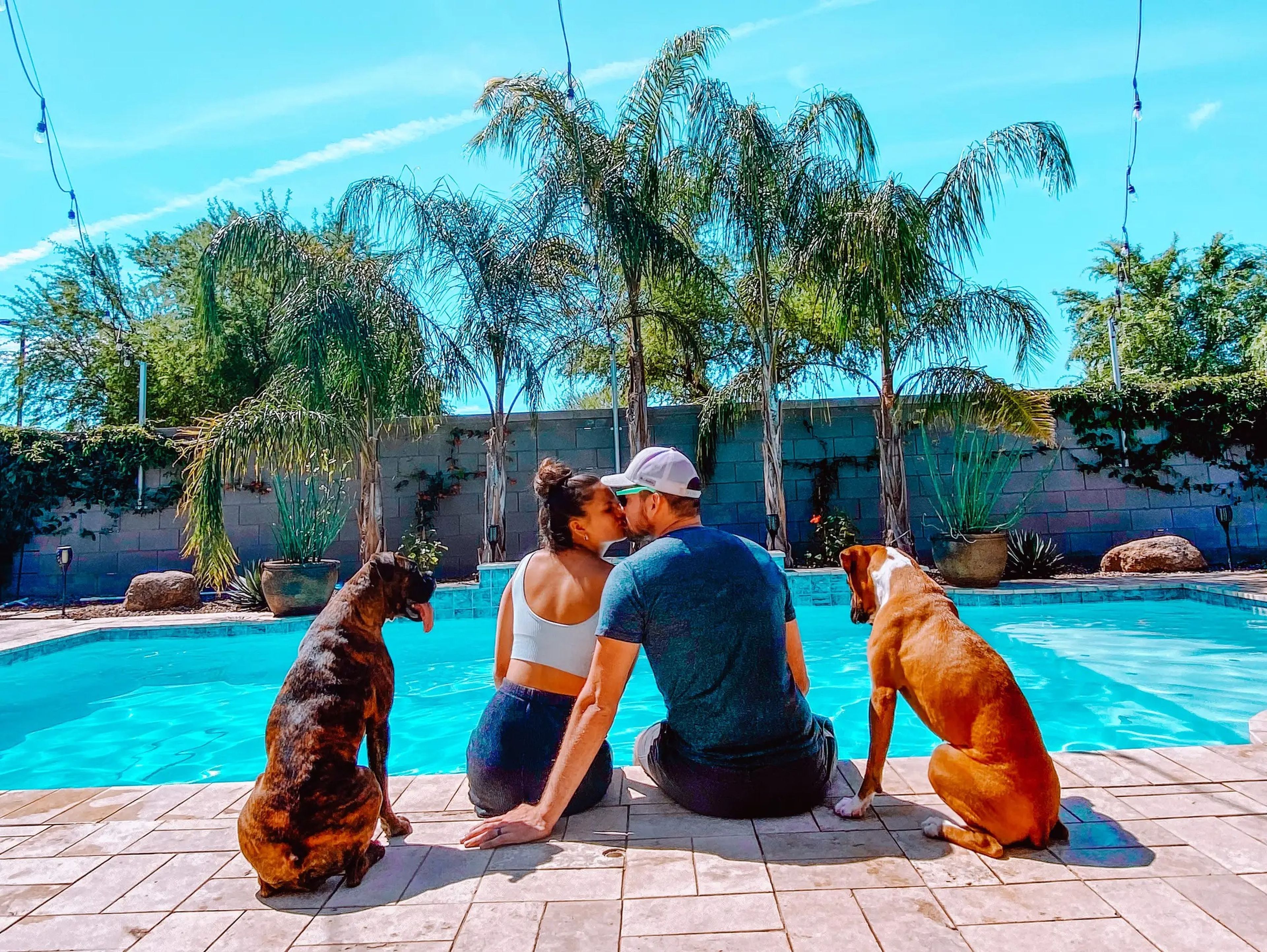 Hannah and Joseph Ryan sitting by a pool with two dogs.