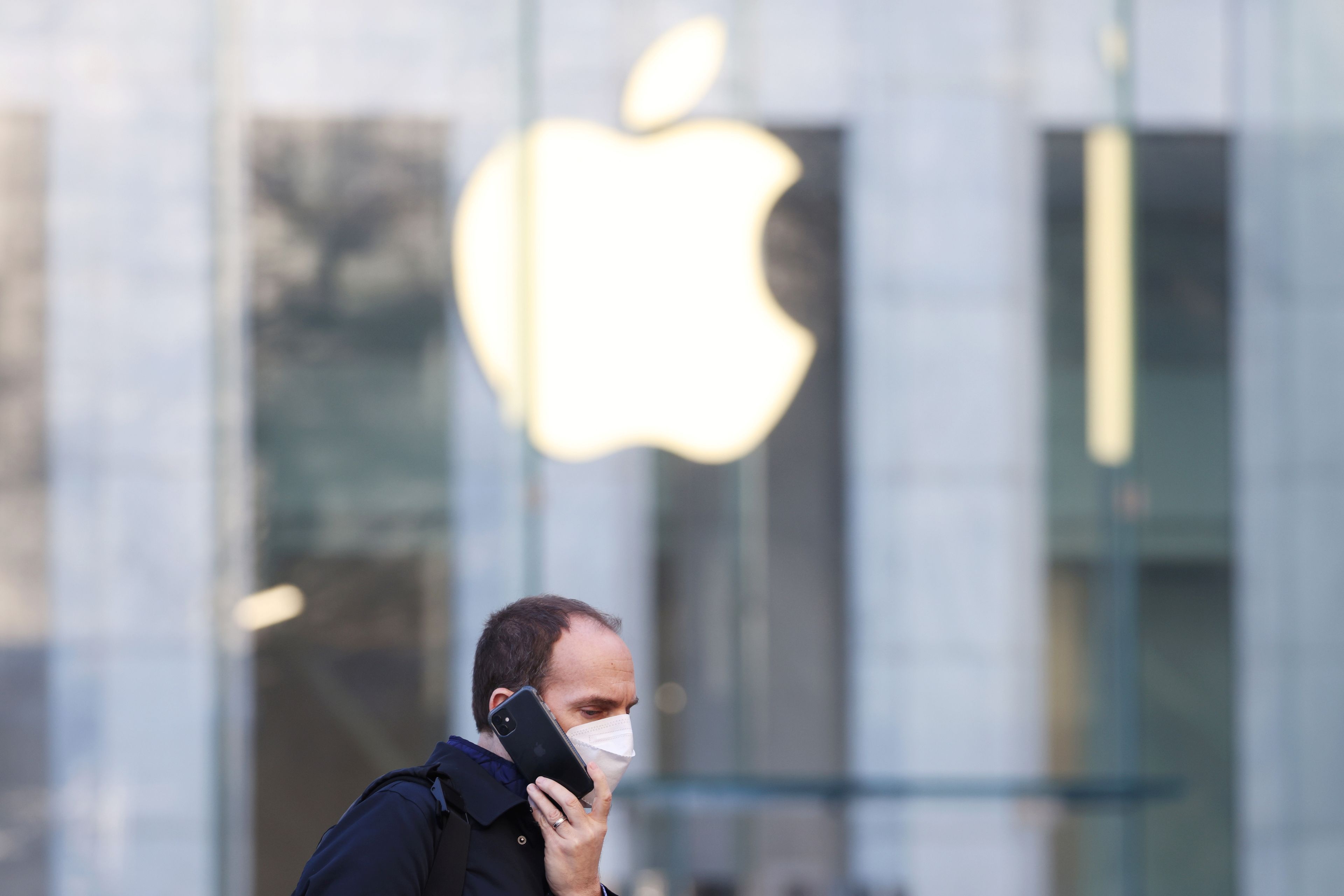 Un hombre habla con un smartphone, con el logo de Apple detrás
