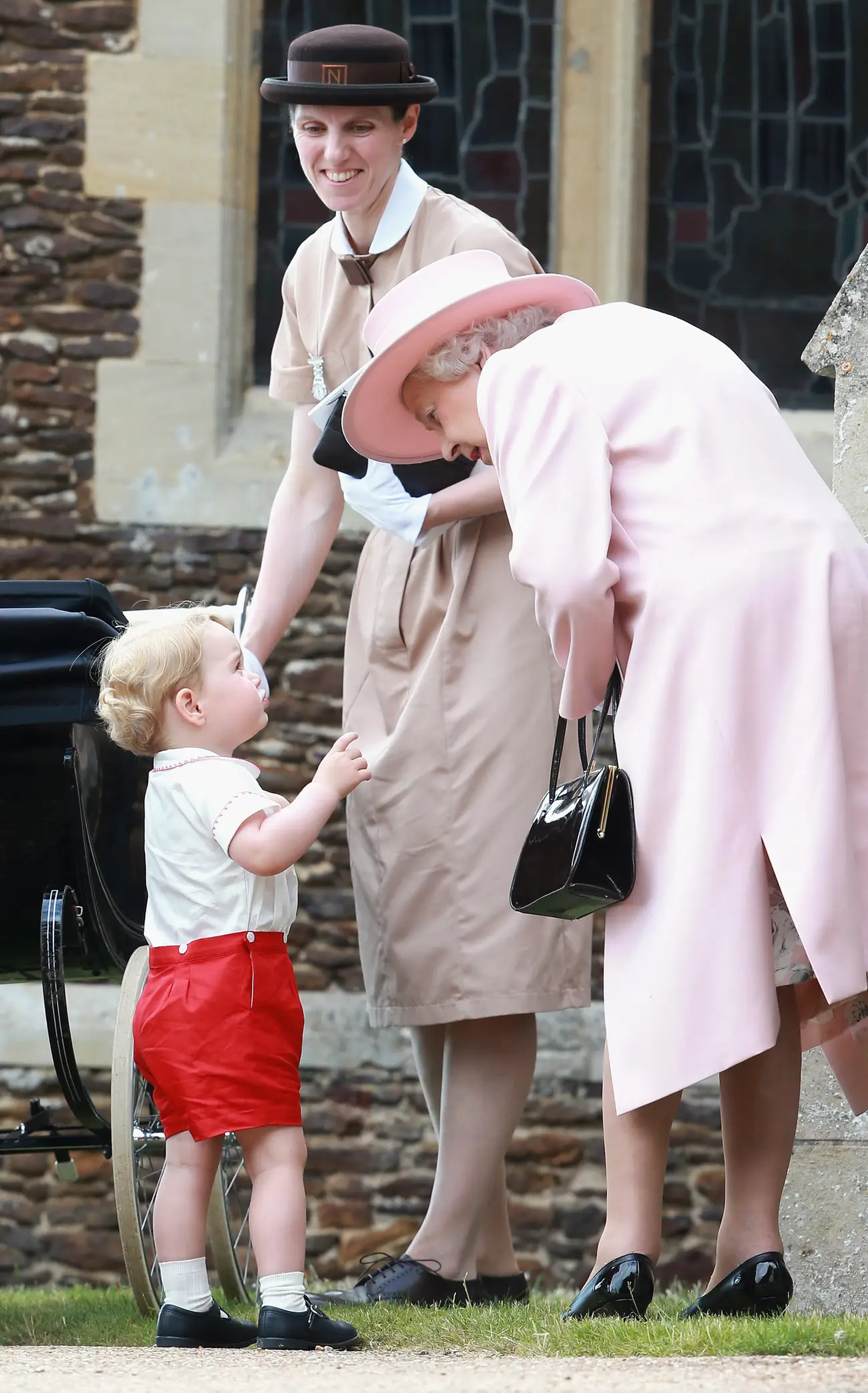 El príncipe Jorge de Cambridge habla con la reina Isabel en el bautizo de la princesa Charlotte en 2015.