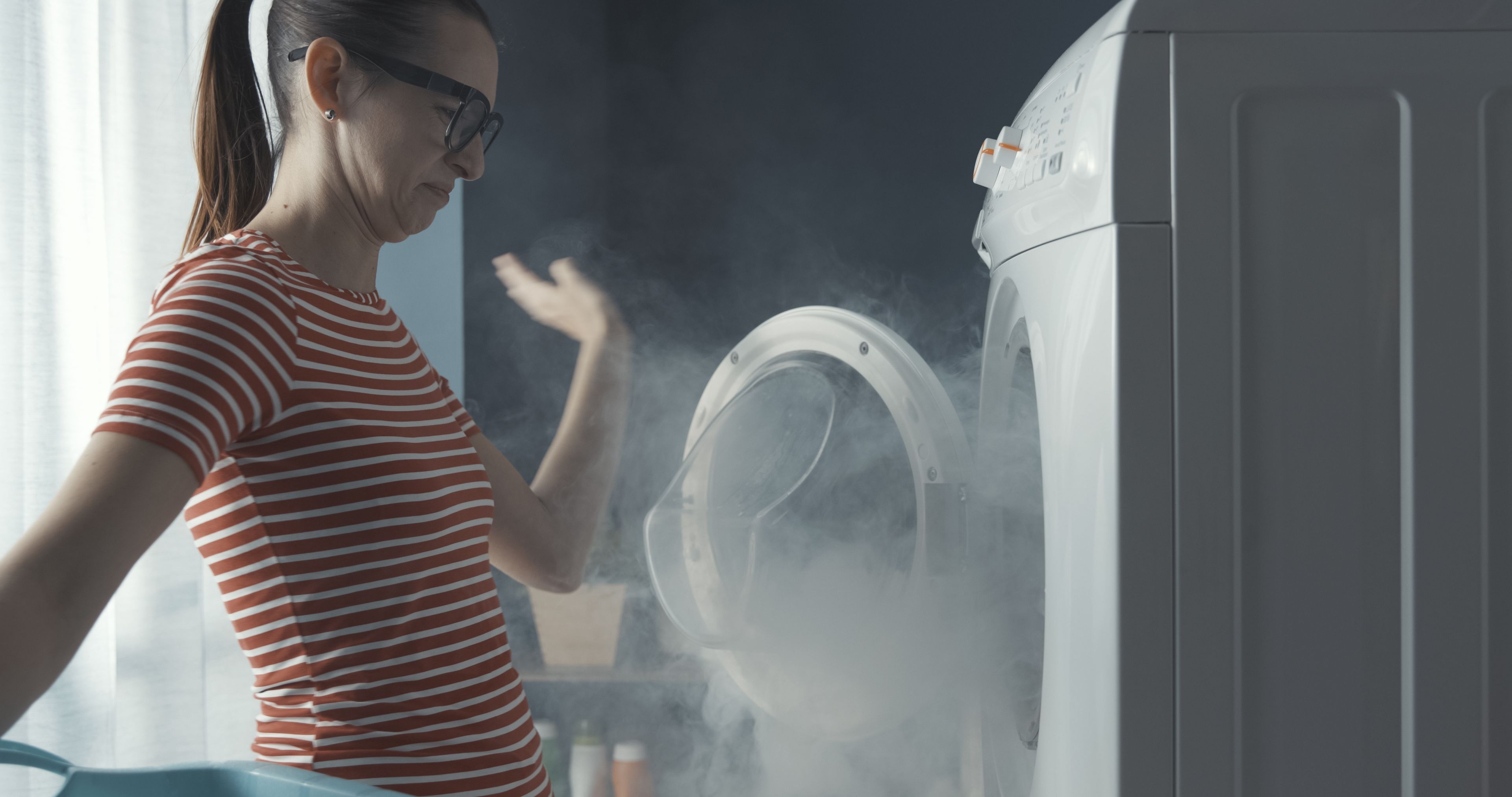 A una mujer le molesta el vapor que sale al abrir la lavadora.