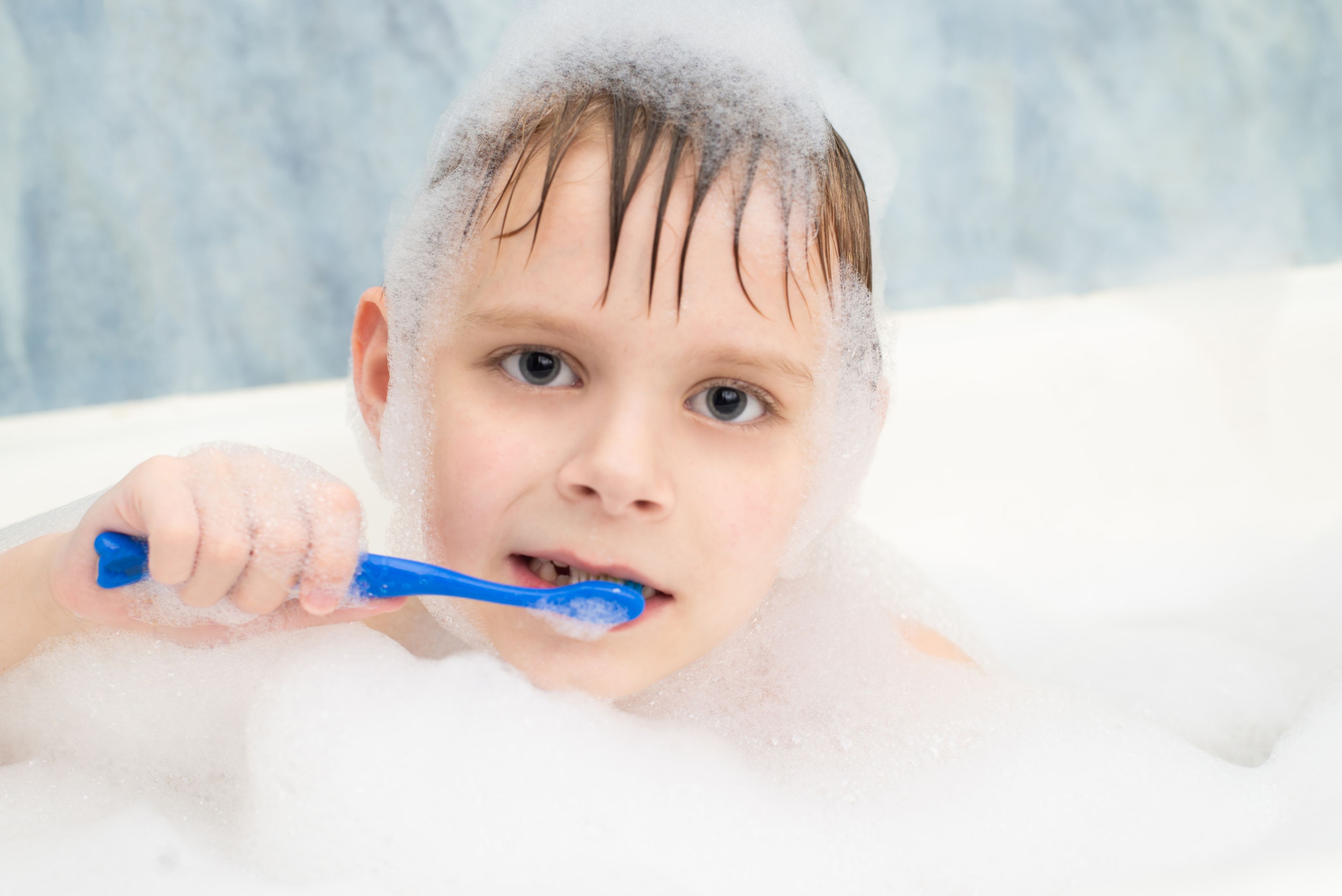 Niño cepillándose los dientes mientras se baña