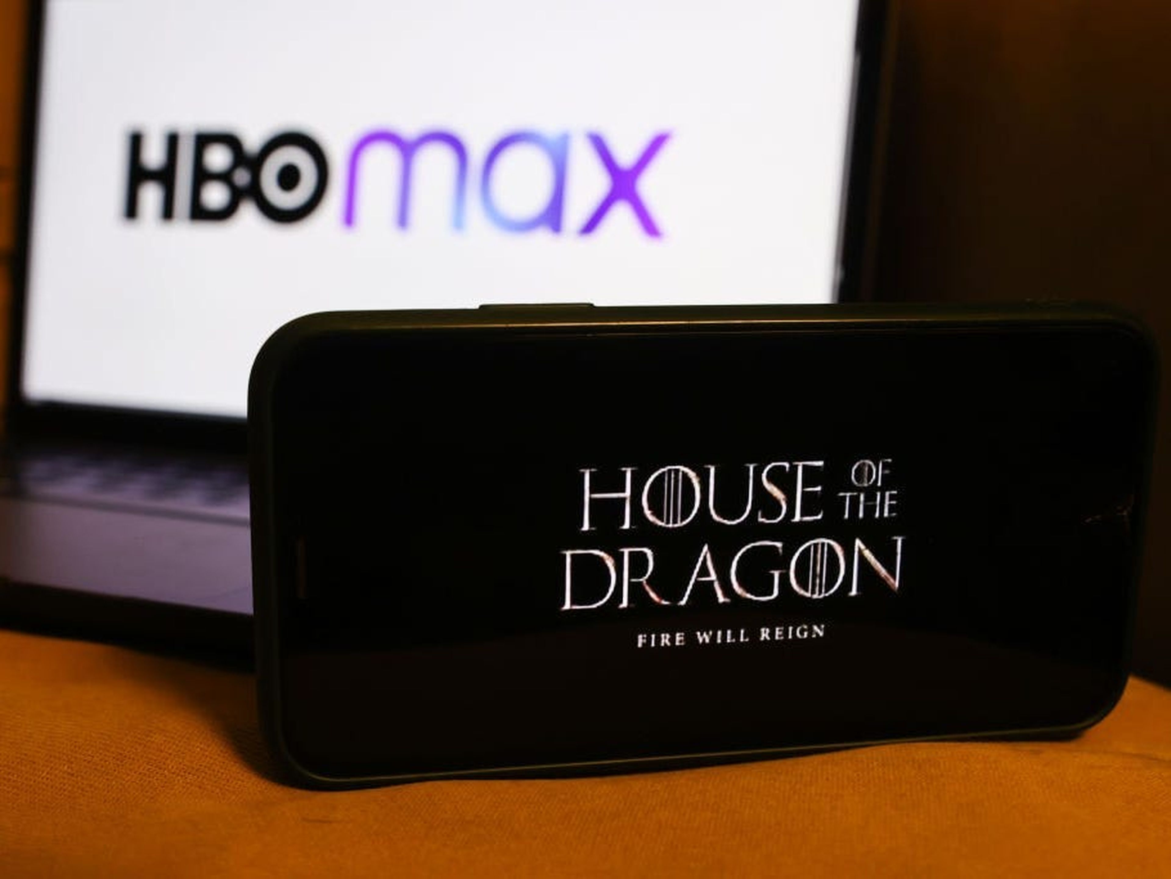 Una pantalla de teléfono muestra el logotipo de 'La casa del dragón' frente a un ordenador con el logotipo de HBO Max.