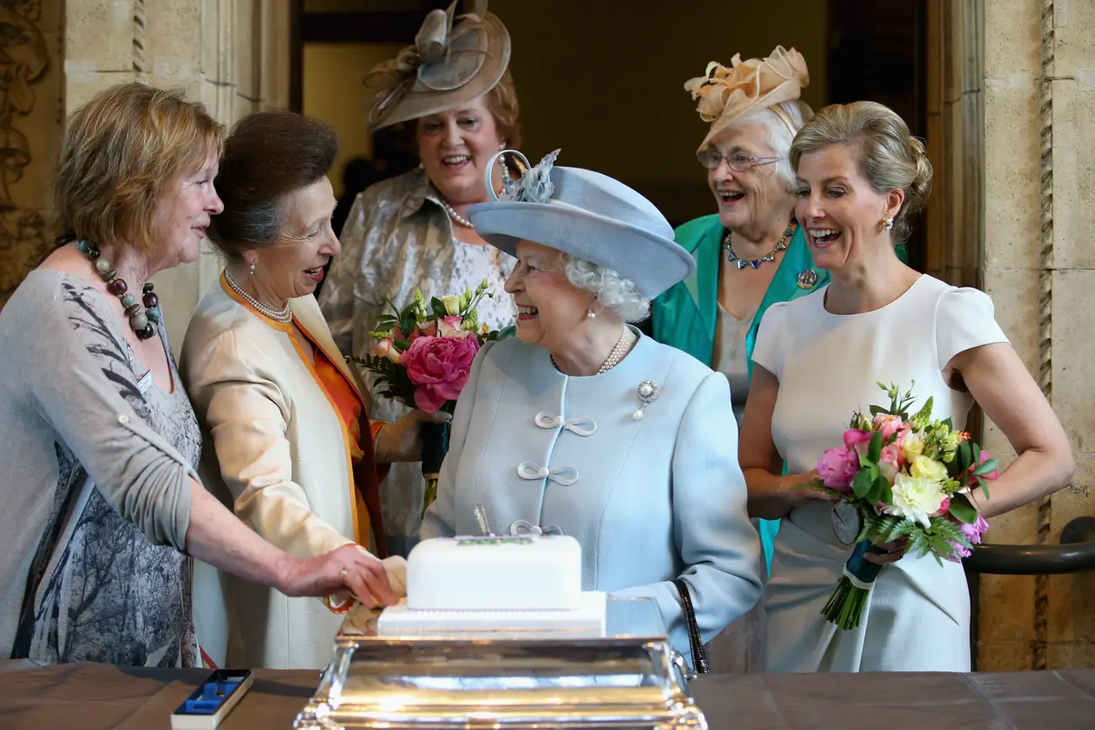 Sophie, la condesa de Wessex y la princesa Ana observan cómo la reina Isabel corta un pastel para celebrar los 100 años del Instituto de la Mujer en el Royal Albert Hall en 2015.
