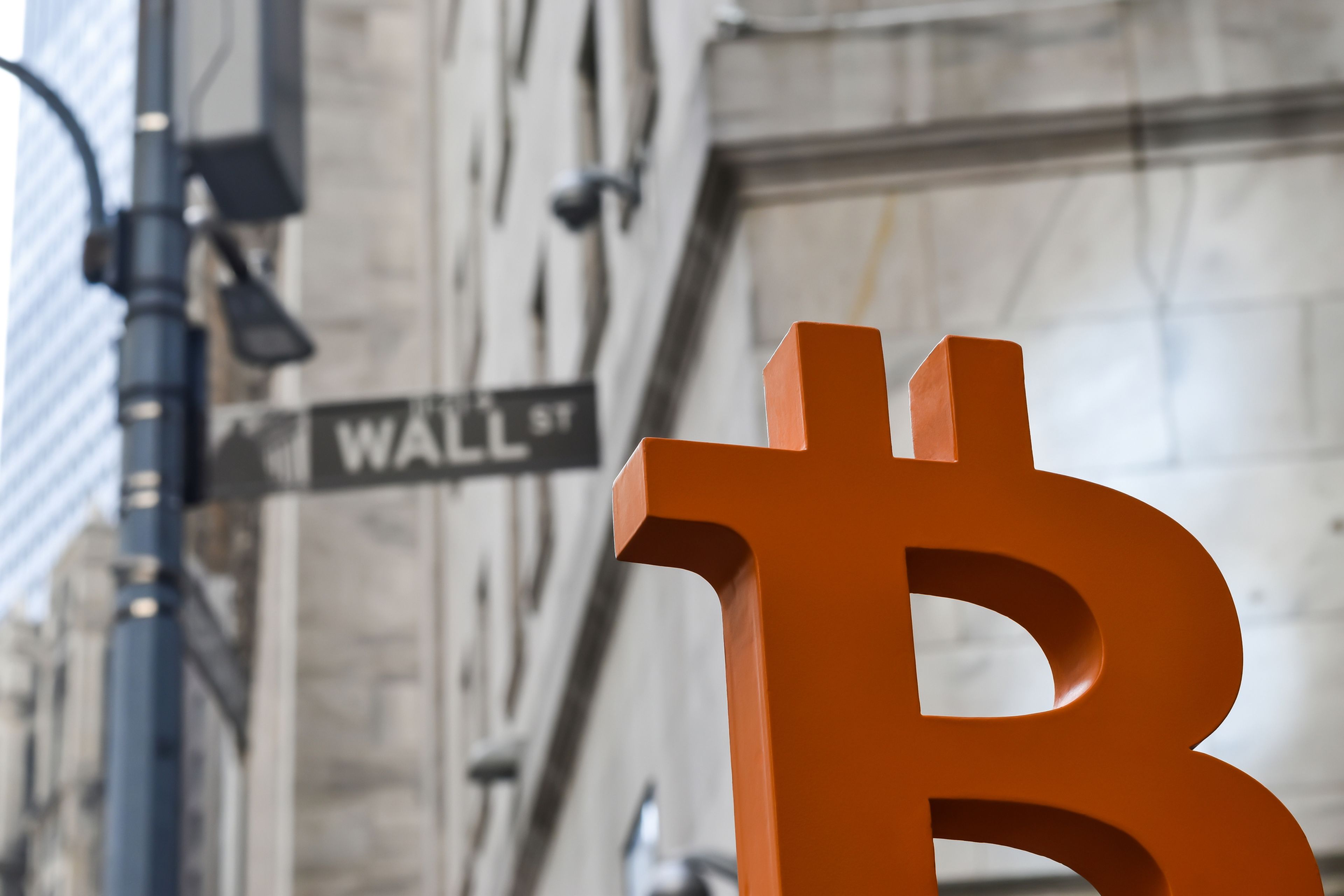 Símbolo de bitcoin delante de una señal de Wall Street St.