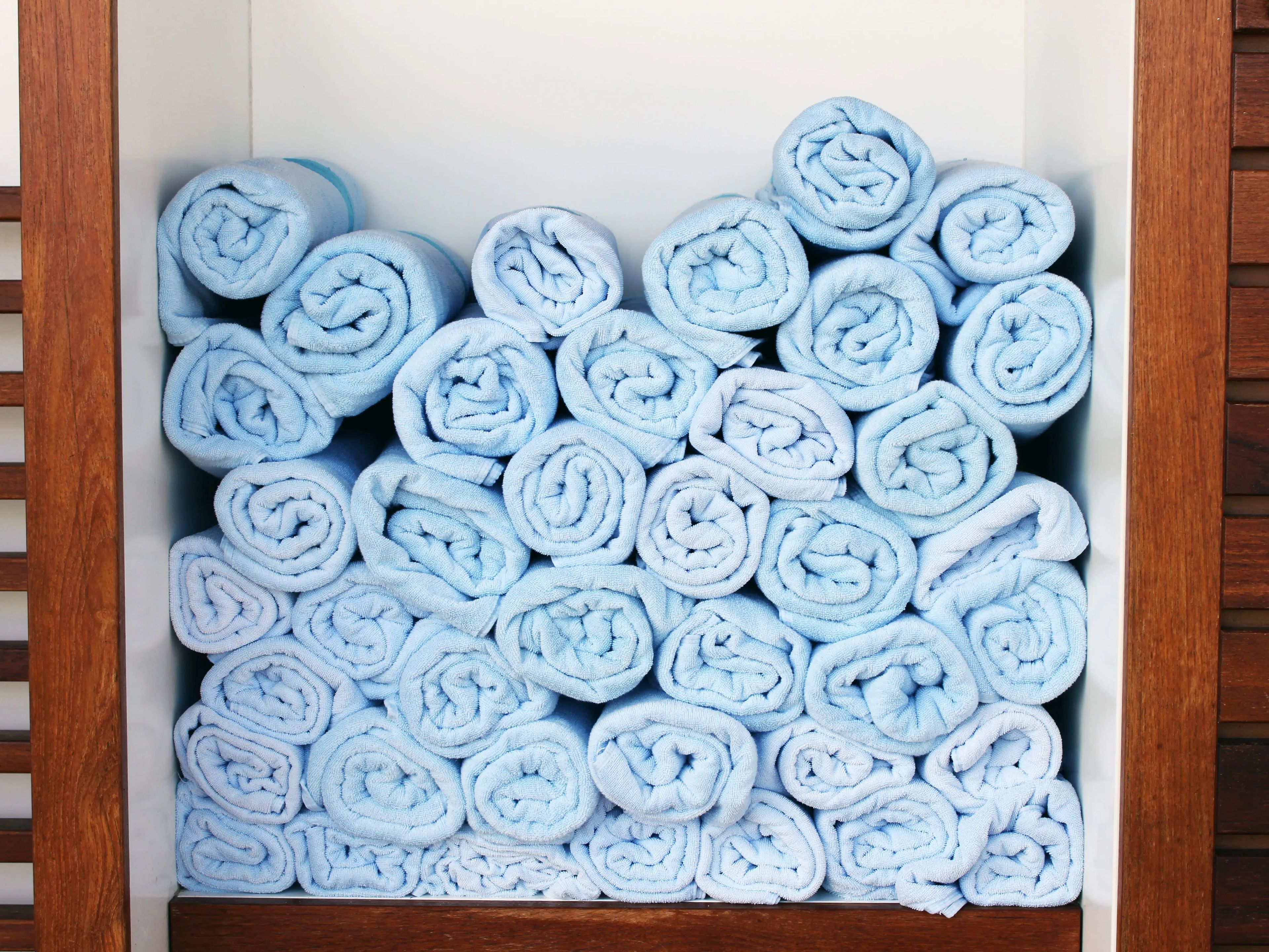 Stack of rolled blue pool towels in wooden holder