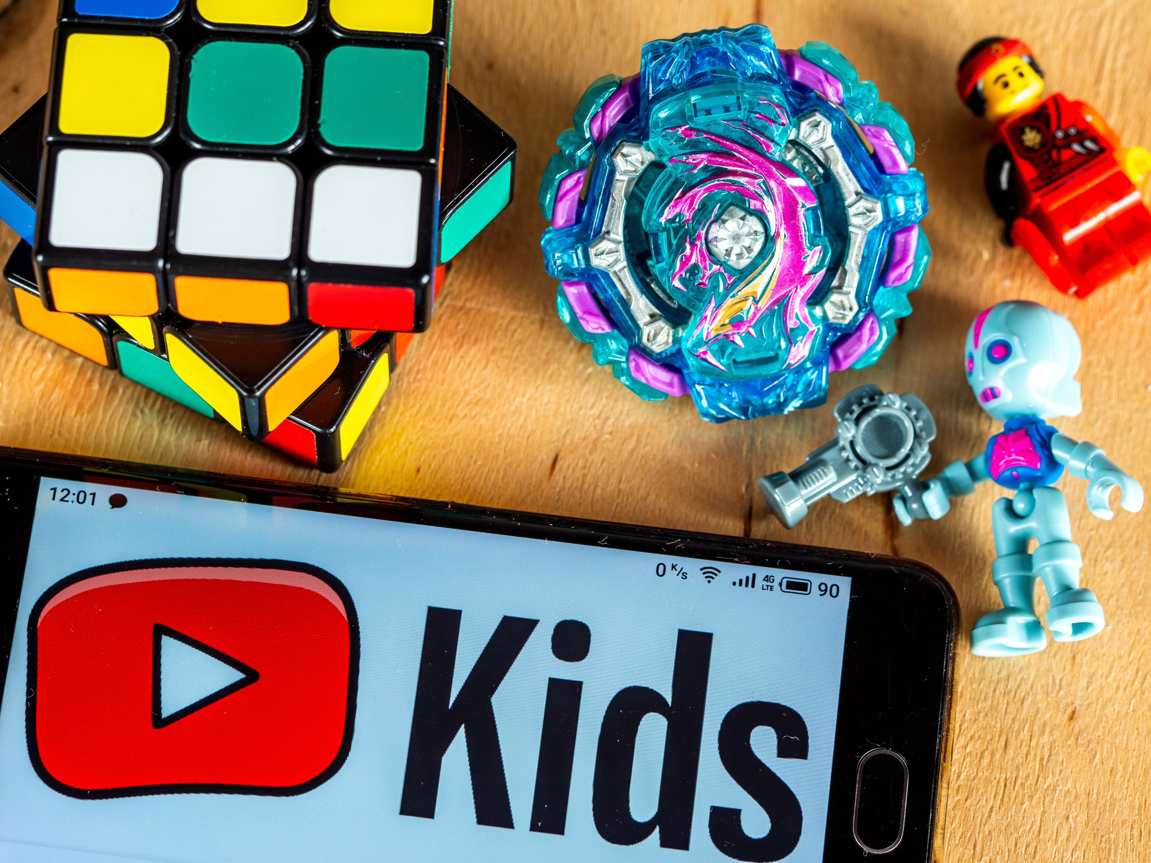 YouTube Kids en un smartphone junto a una serie de juguetes para niños.