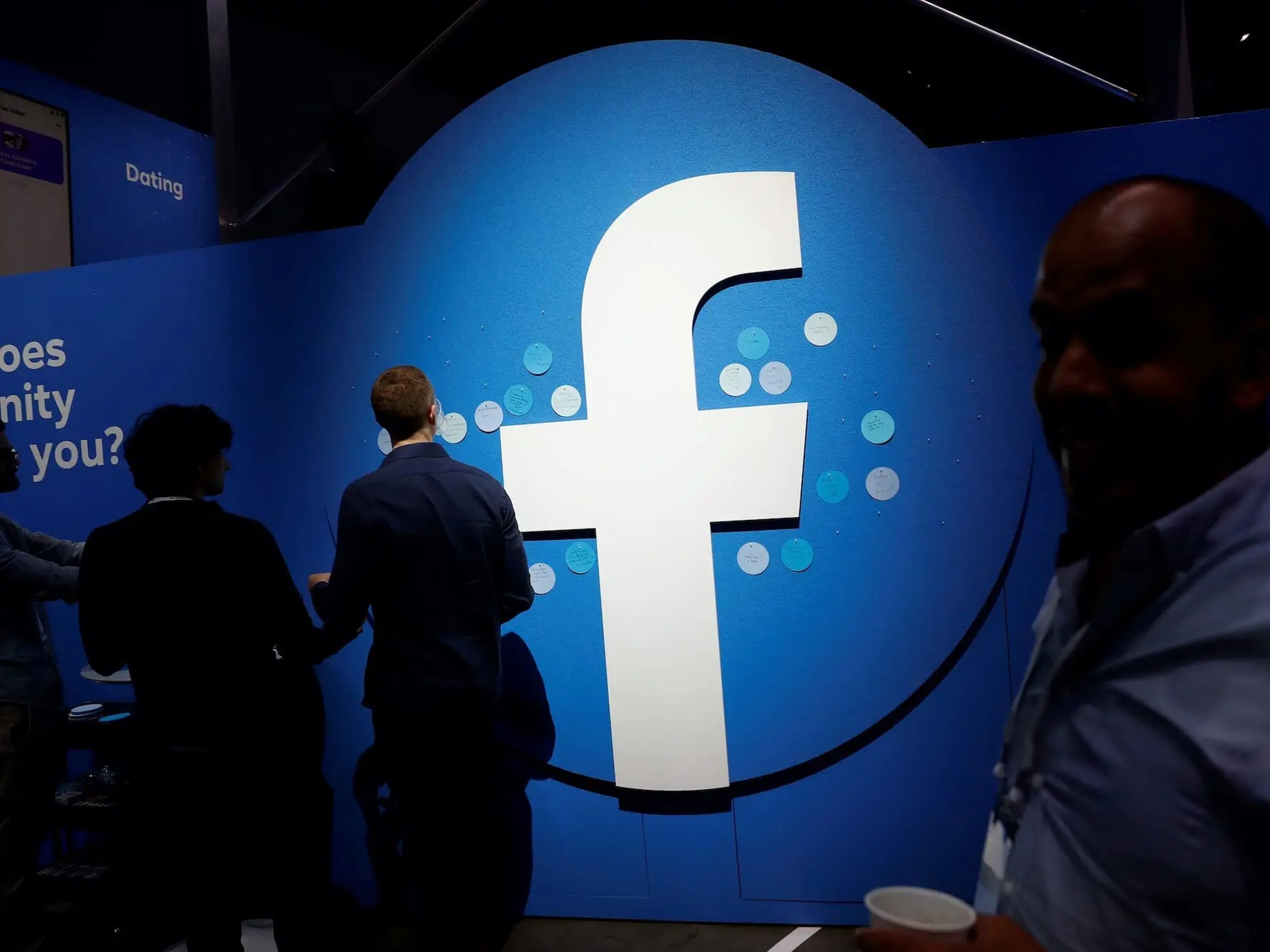 Los asistentes pasan por delante de un logotipo de Facebook durante la conferencia de desarrolladores F8 de Facebook Inc en 2019.