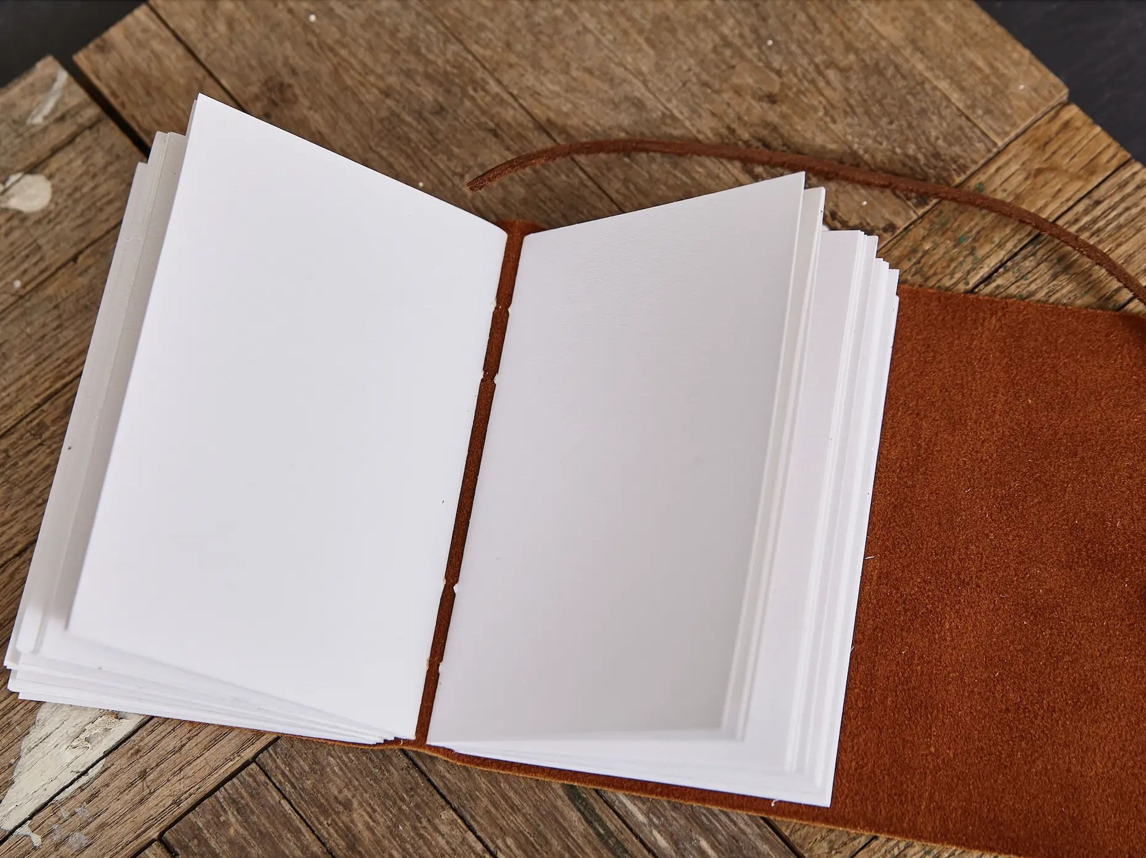 blank leather-bound journal sitting open on a wooden surface