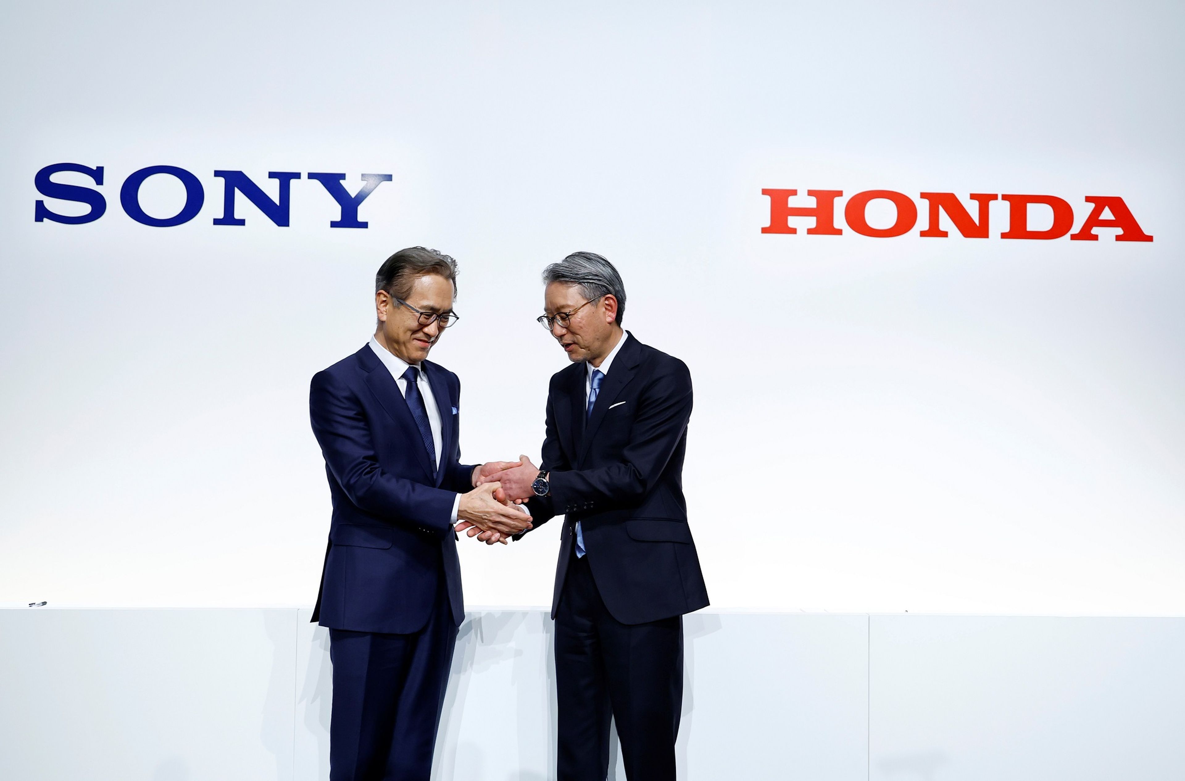 El director ejecutivo de Sony Corp (izq.), Kenichiro Yoshida, estrecha la mano de Toshihiro Mibe, de Honda Motor.