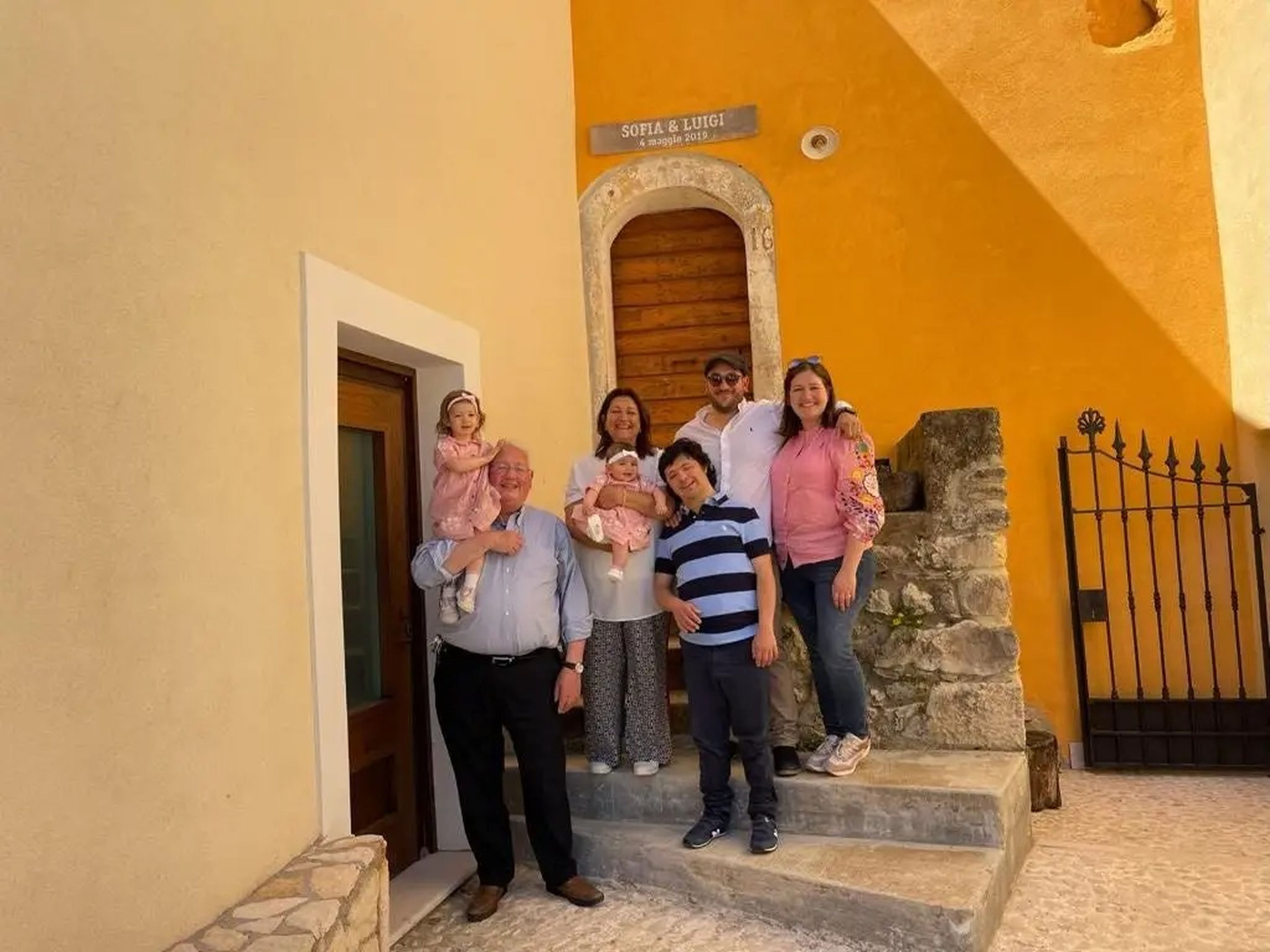a family photo outside a yellow building