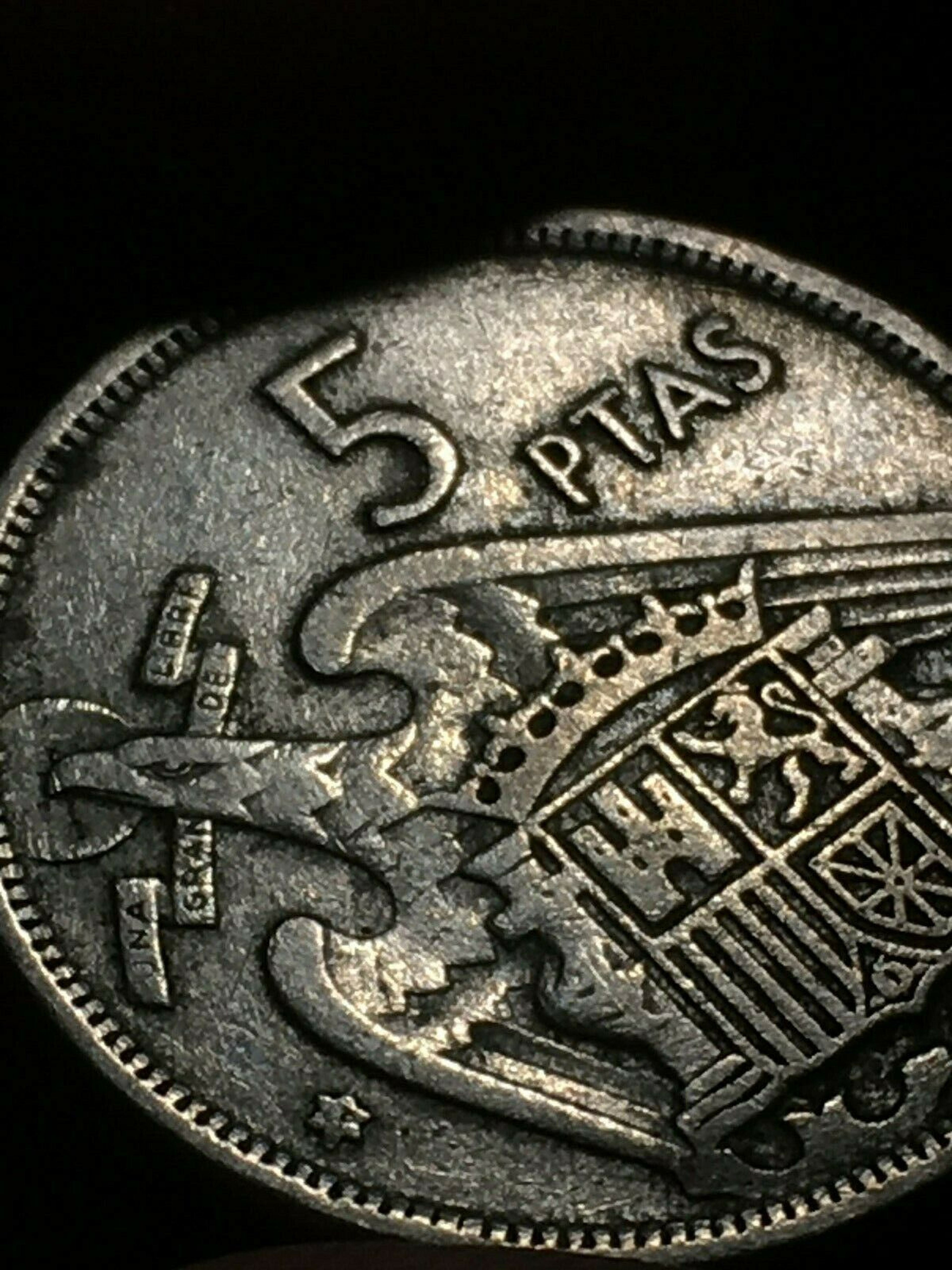 Reverso de la moneda de 5 pesetas de 1957, con el escudo de España y los elementos franquistas.