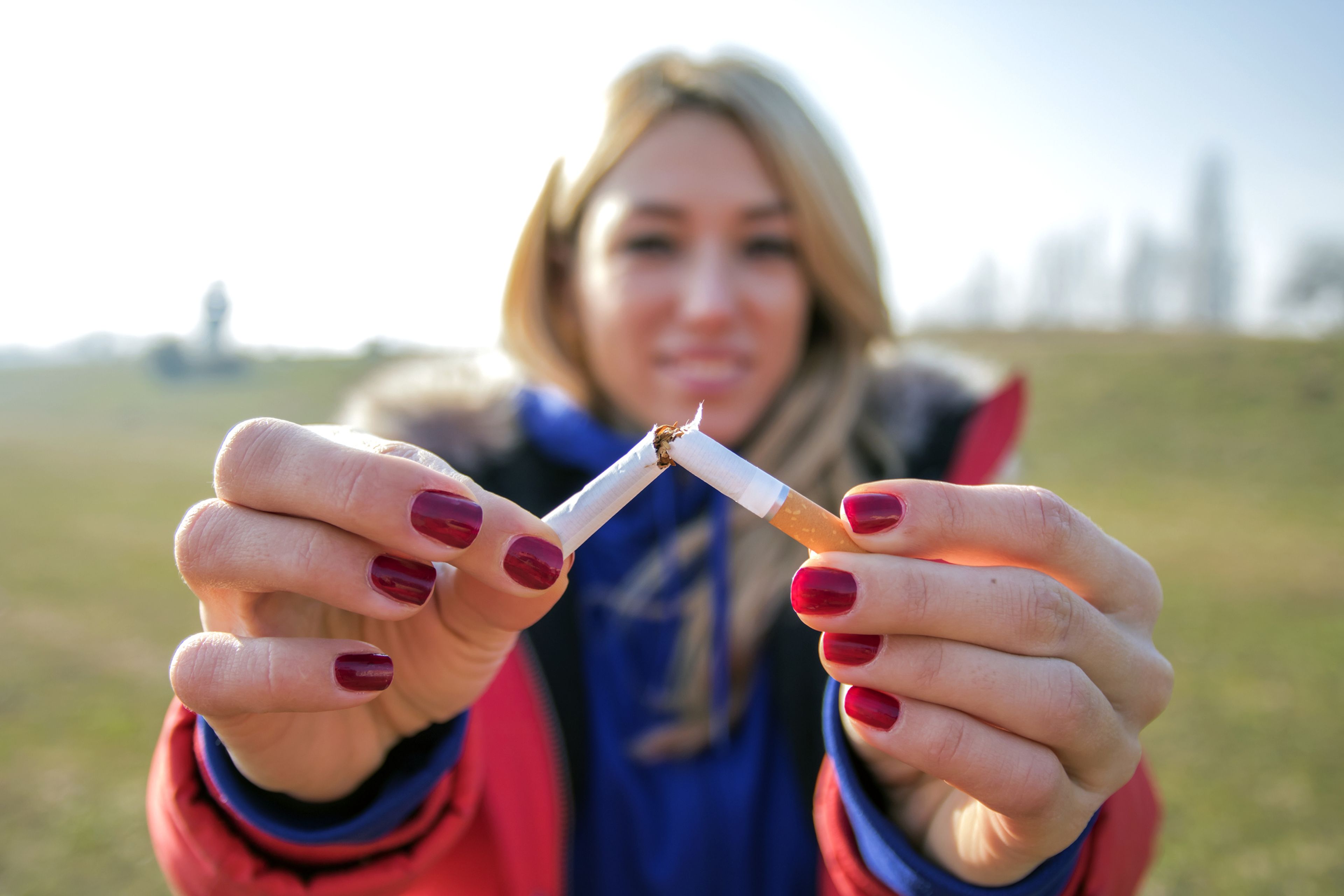 Mujer joven partiendo en dos un cigarro
