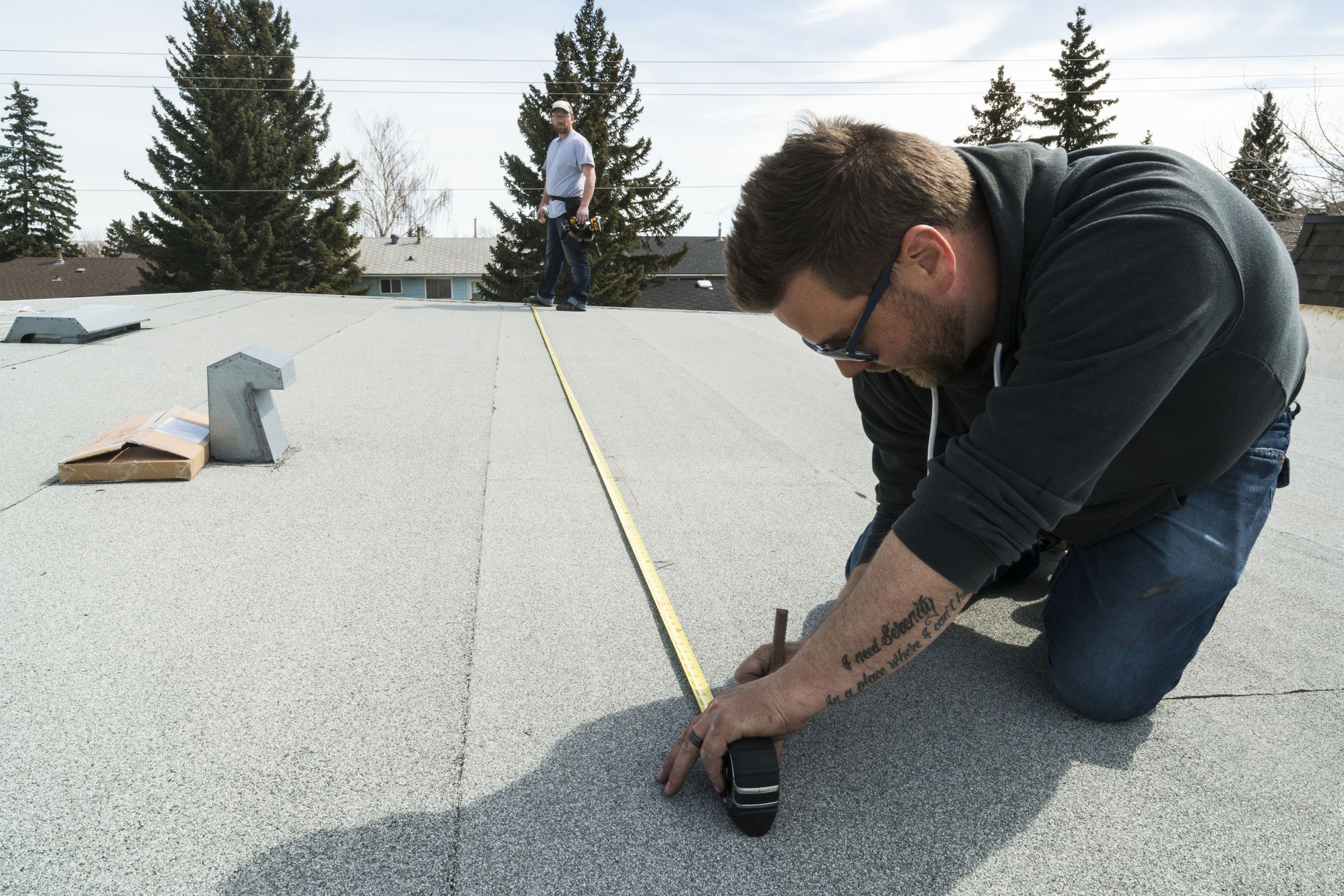 2 personas miden un tejado para instalar placas solares. 