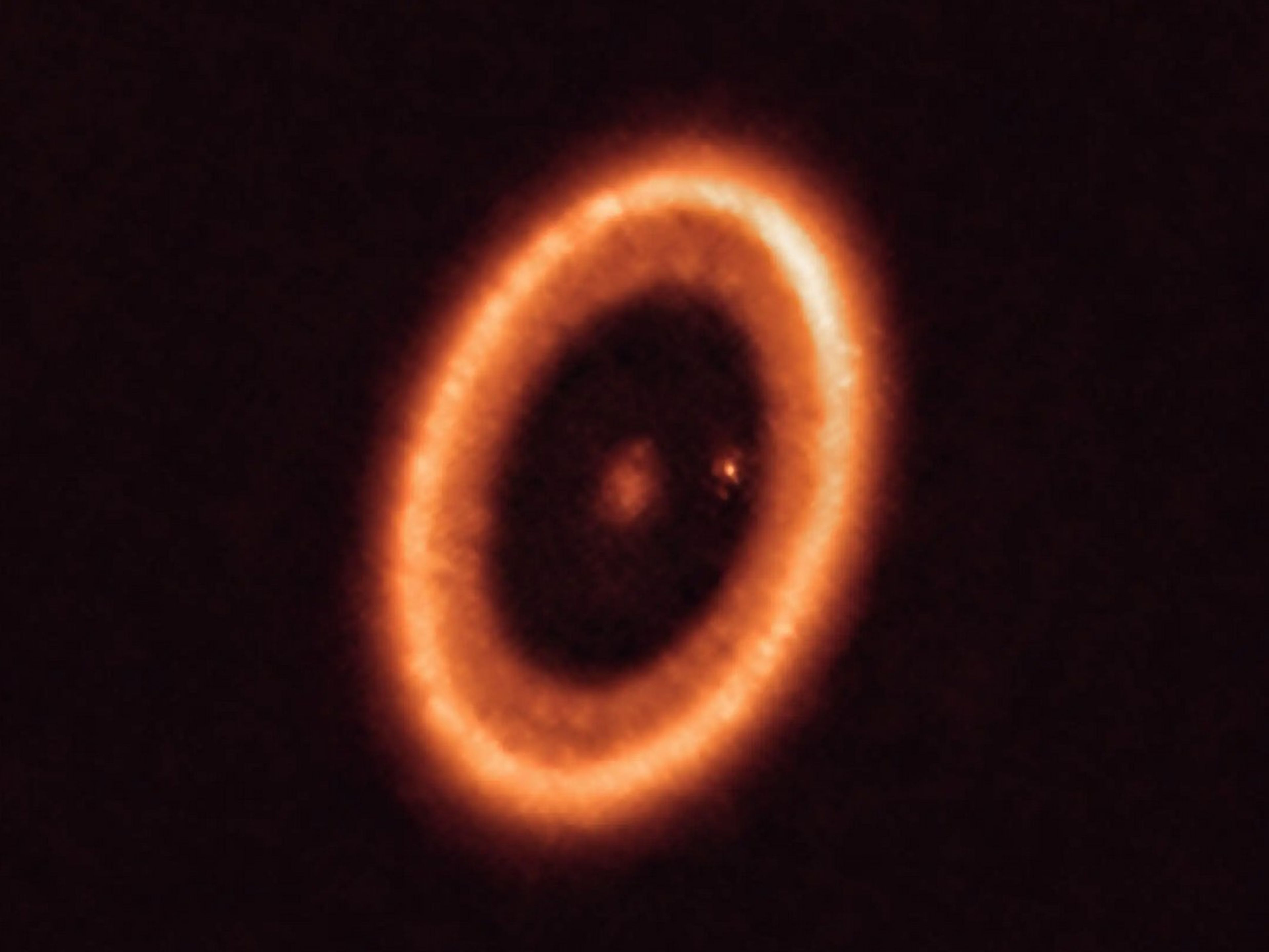 Estrella rodeada por un disco circumplanetario, con un planeta visible a la derecha, capturada por el Atacama Large Millimeter Array.