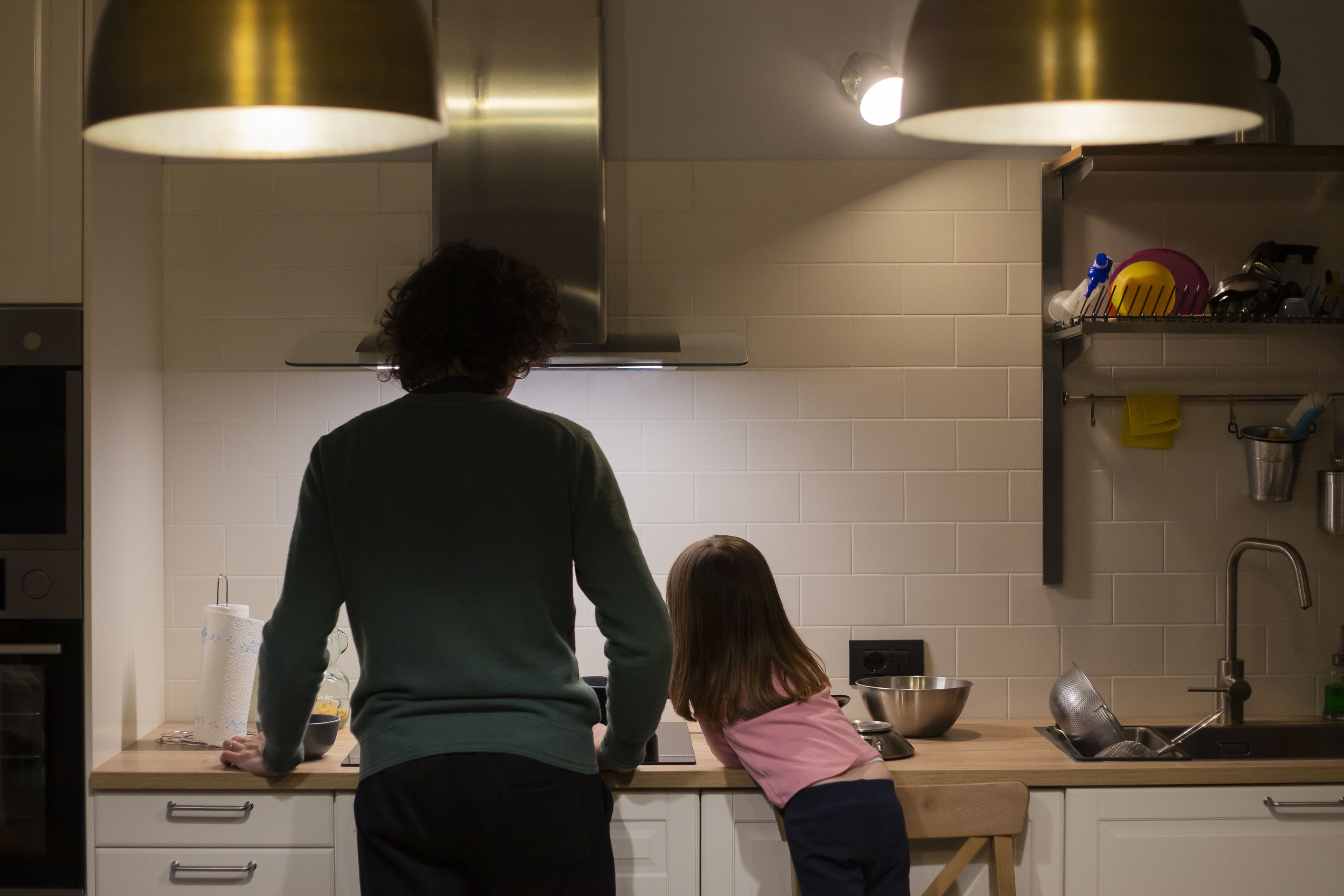 Un hombre cocina con su hija. 