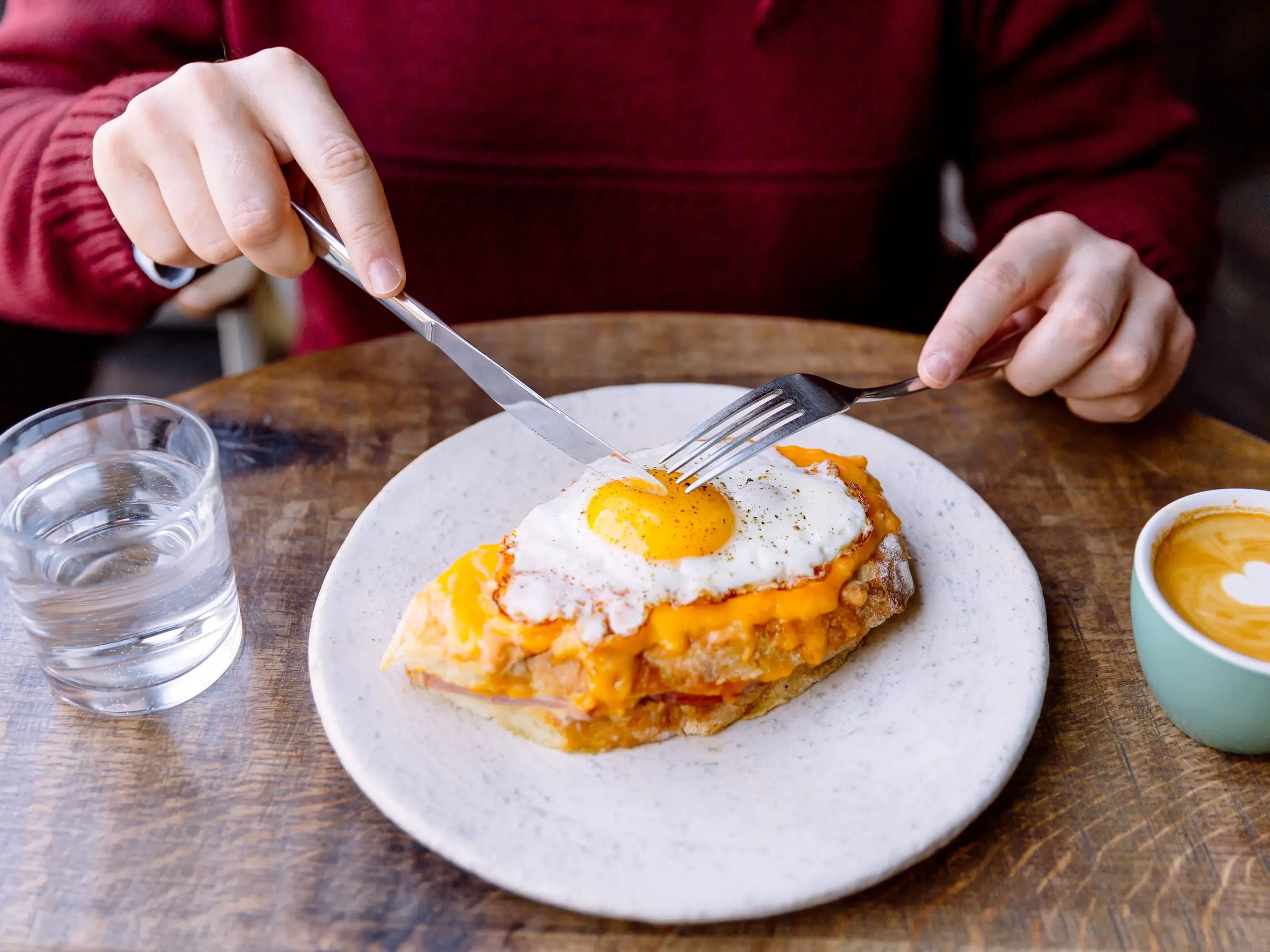 A man eating cheesy eggs on toast.