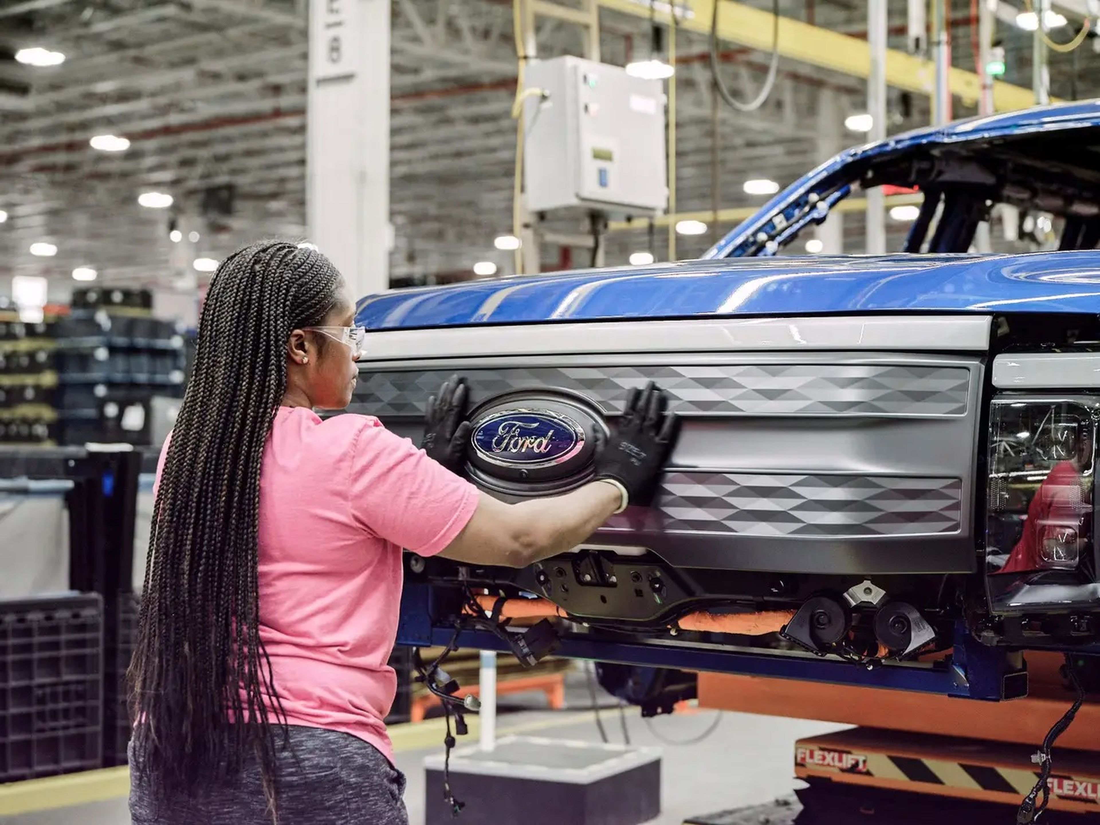Una mujer ensamblando una pieza en una fábrica de Ford.