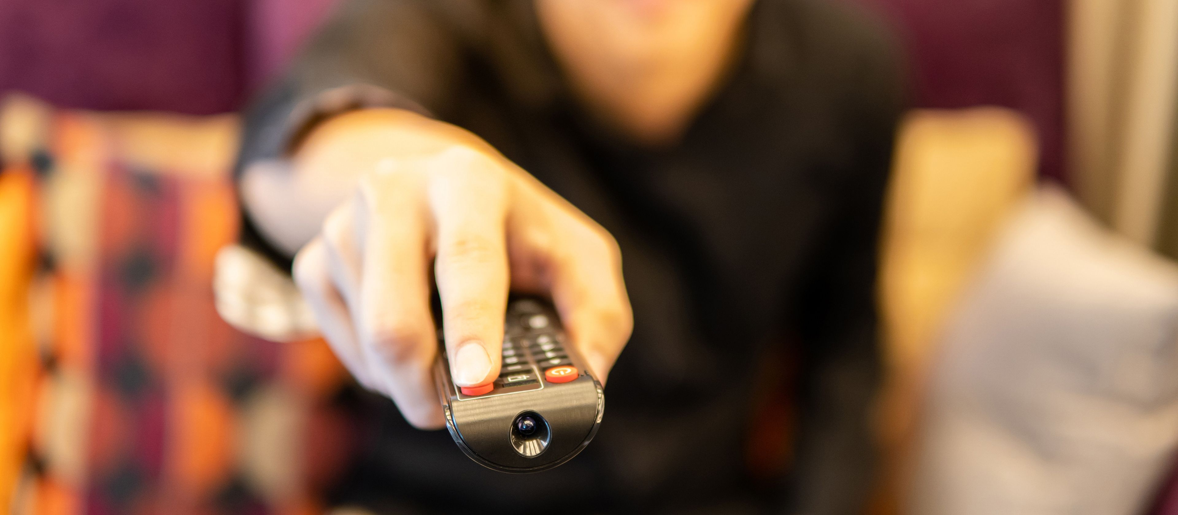 Una persona pulsa un botón en el mando a distancia de la televisión. 