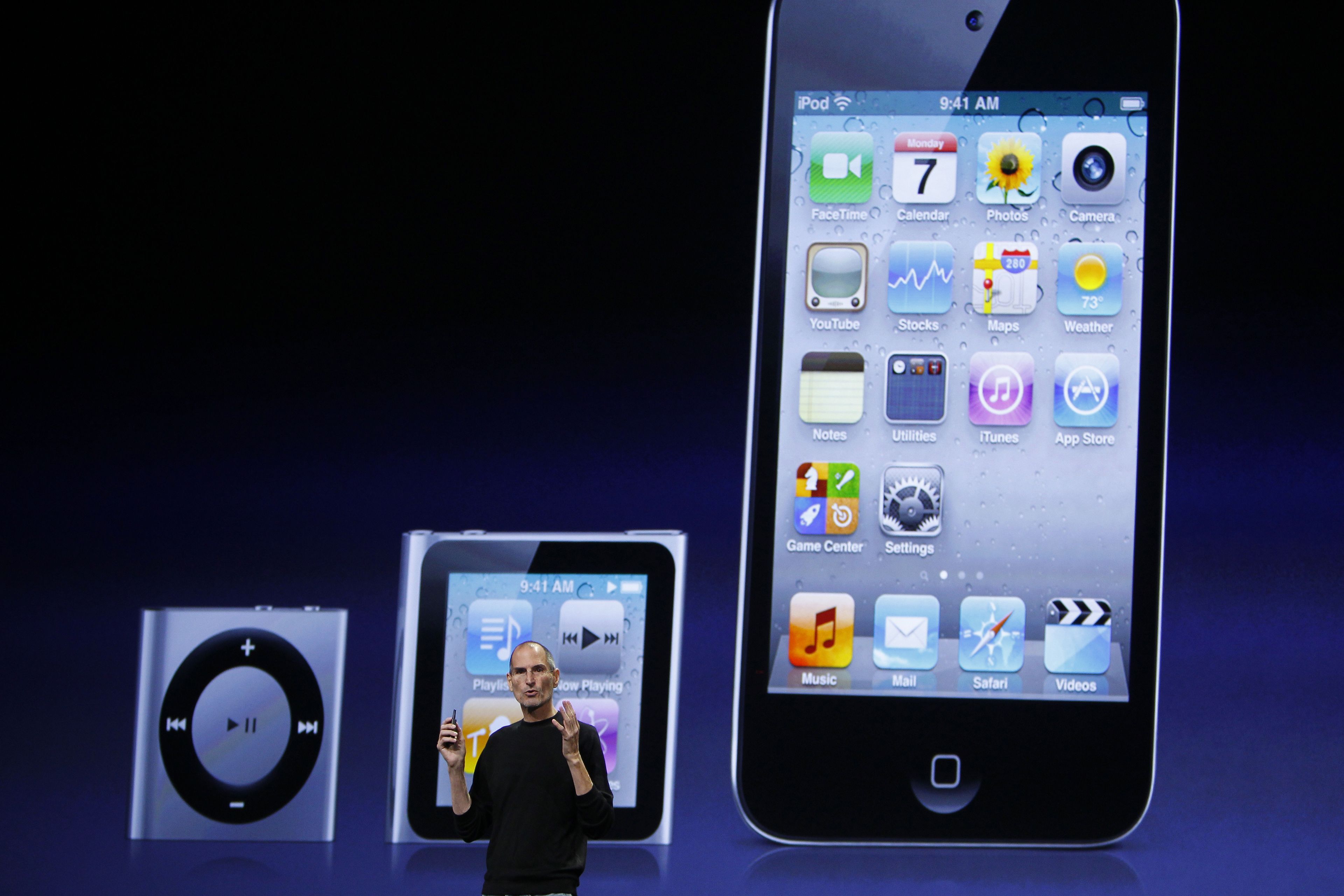 El cofundador y ex-CEO de Apple, Steve Jobs, en una presentación de Apple frente a imágenes de los iPod Shuffle, Nano y Touch.