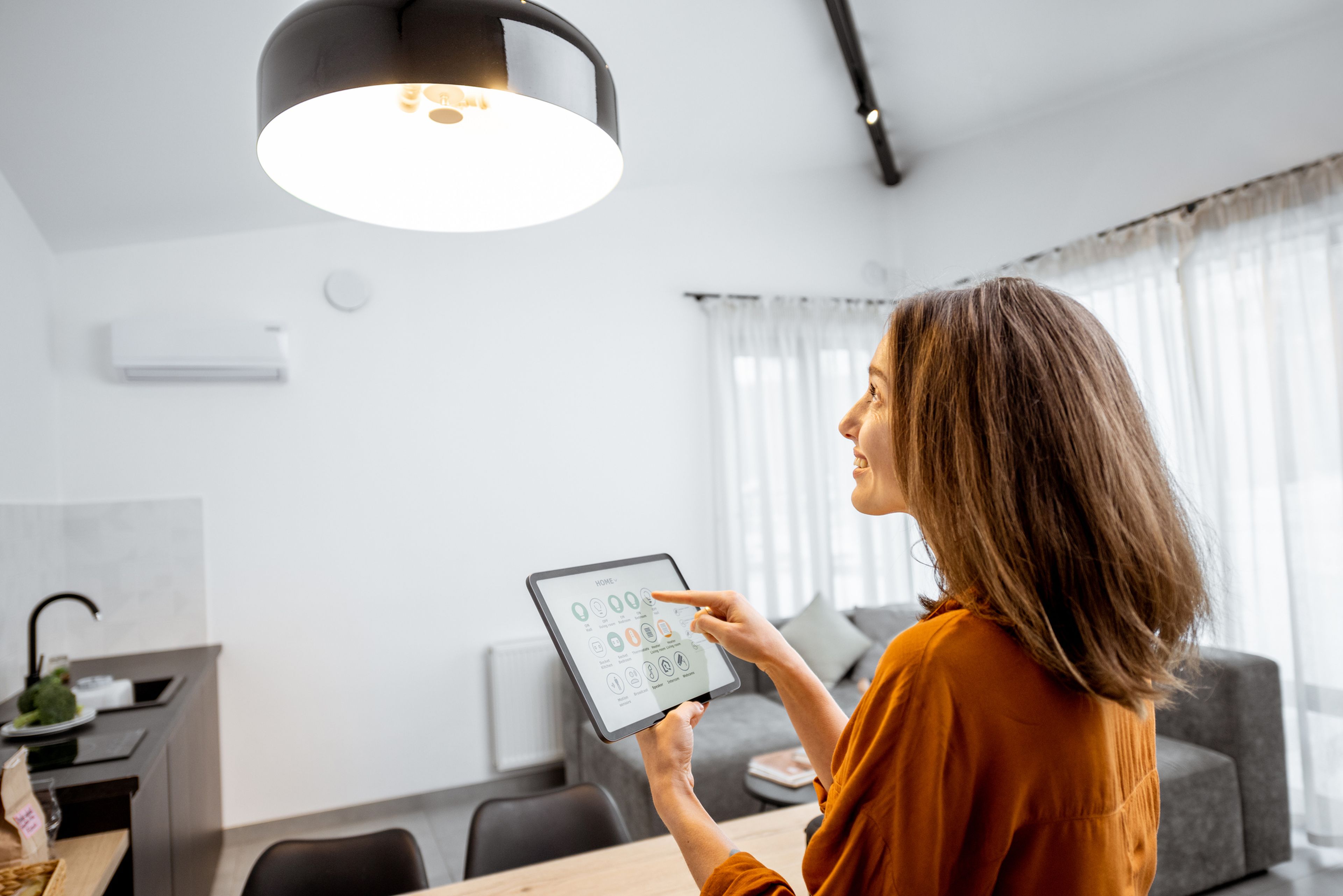 Una mujer controla la luz de casa con una tablet.