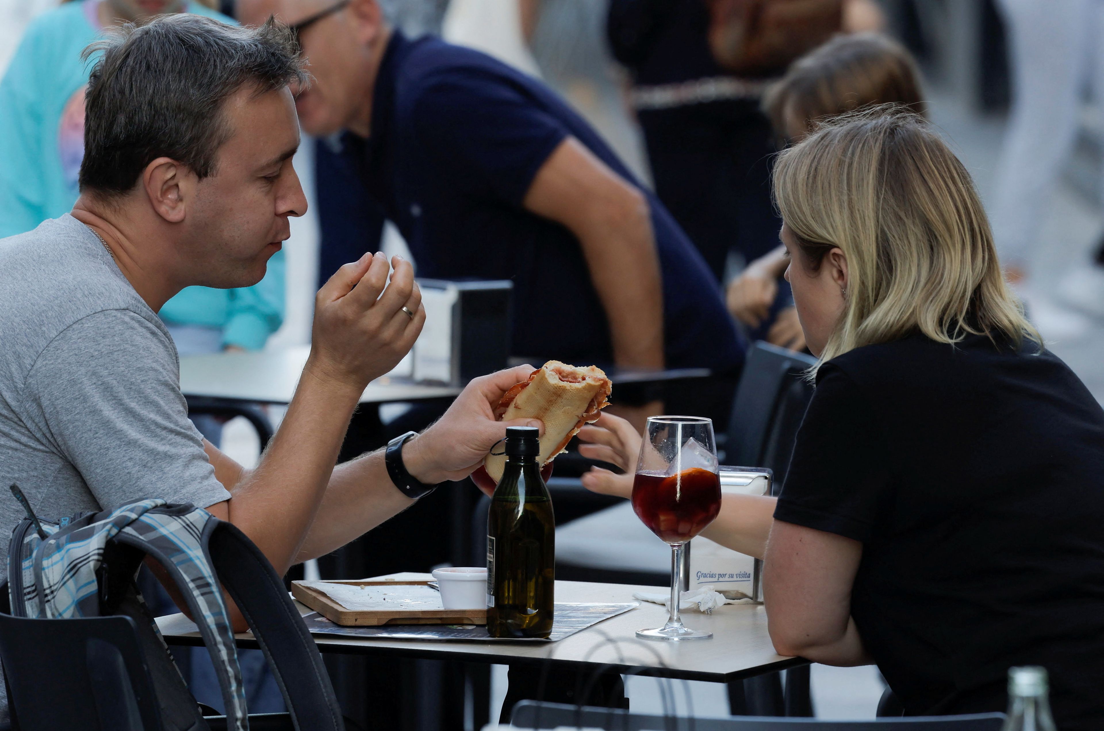 Una pareja come en la terraza de un bar.