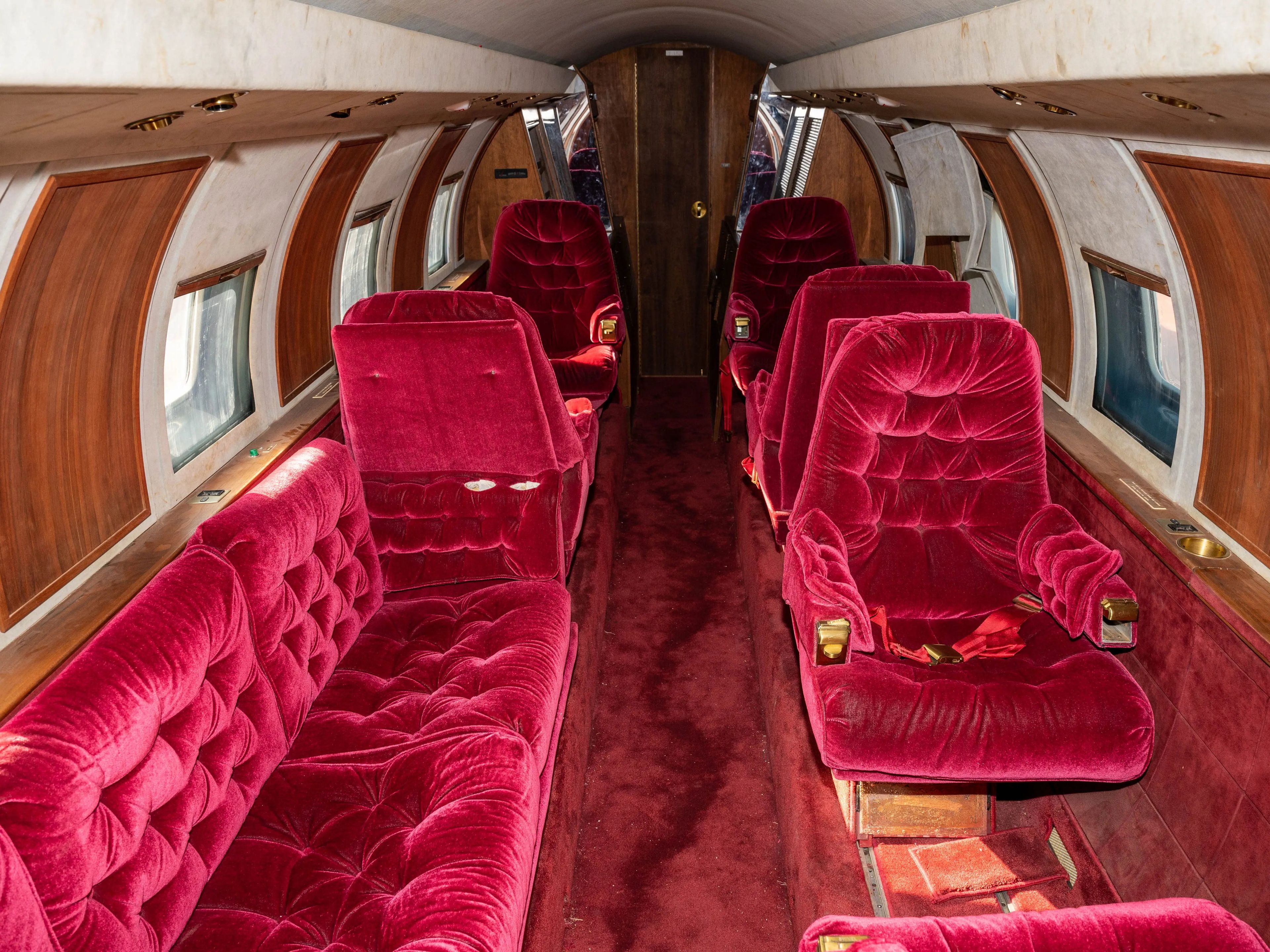 Photo of inside the jet plane which has red velvet seats