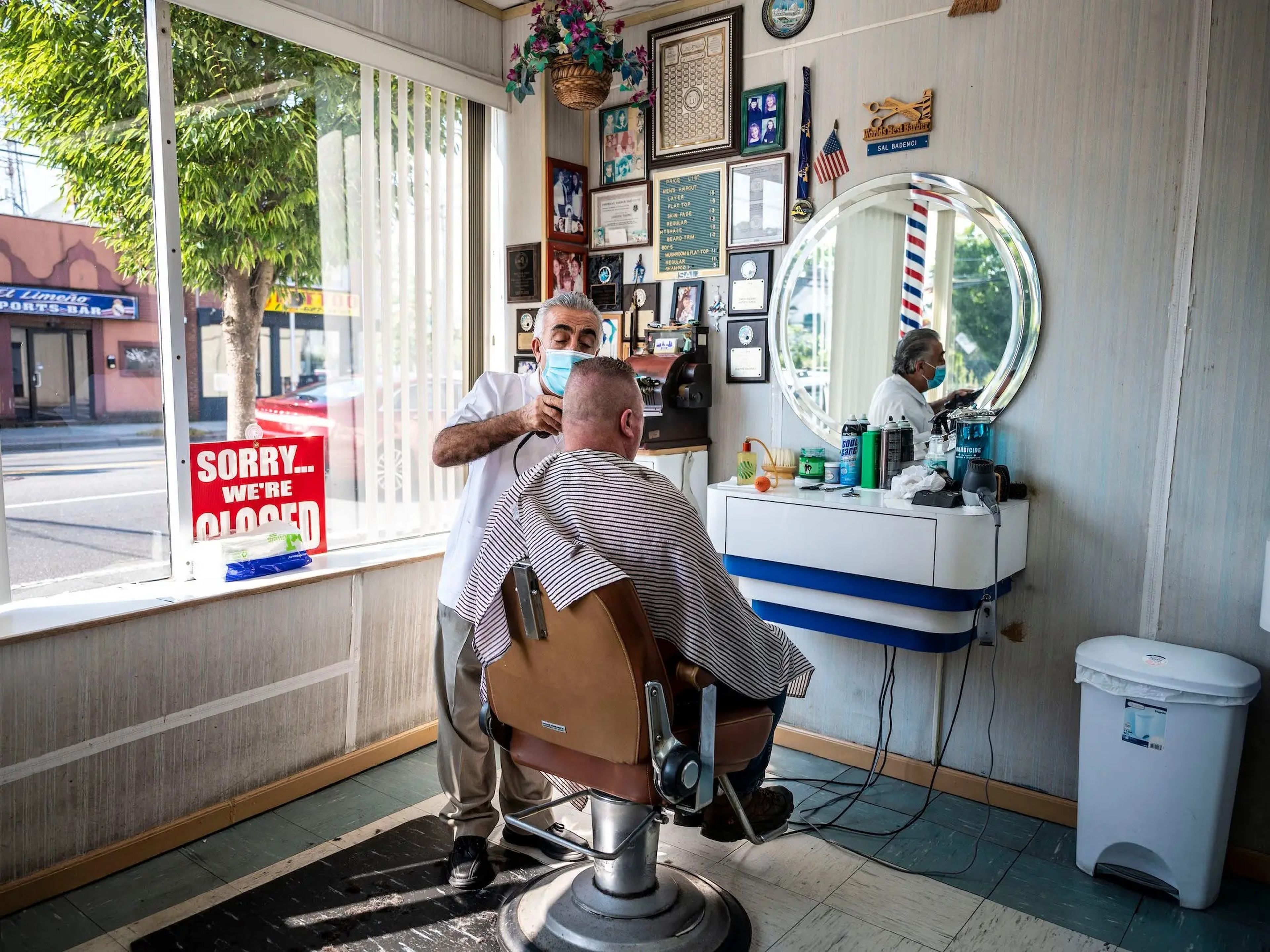 Sal Bademci atiende a un cliente en su barbería de Main St. en Patchogue, Nueva York.