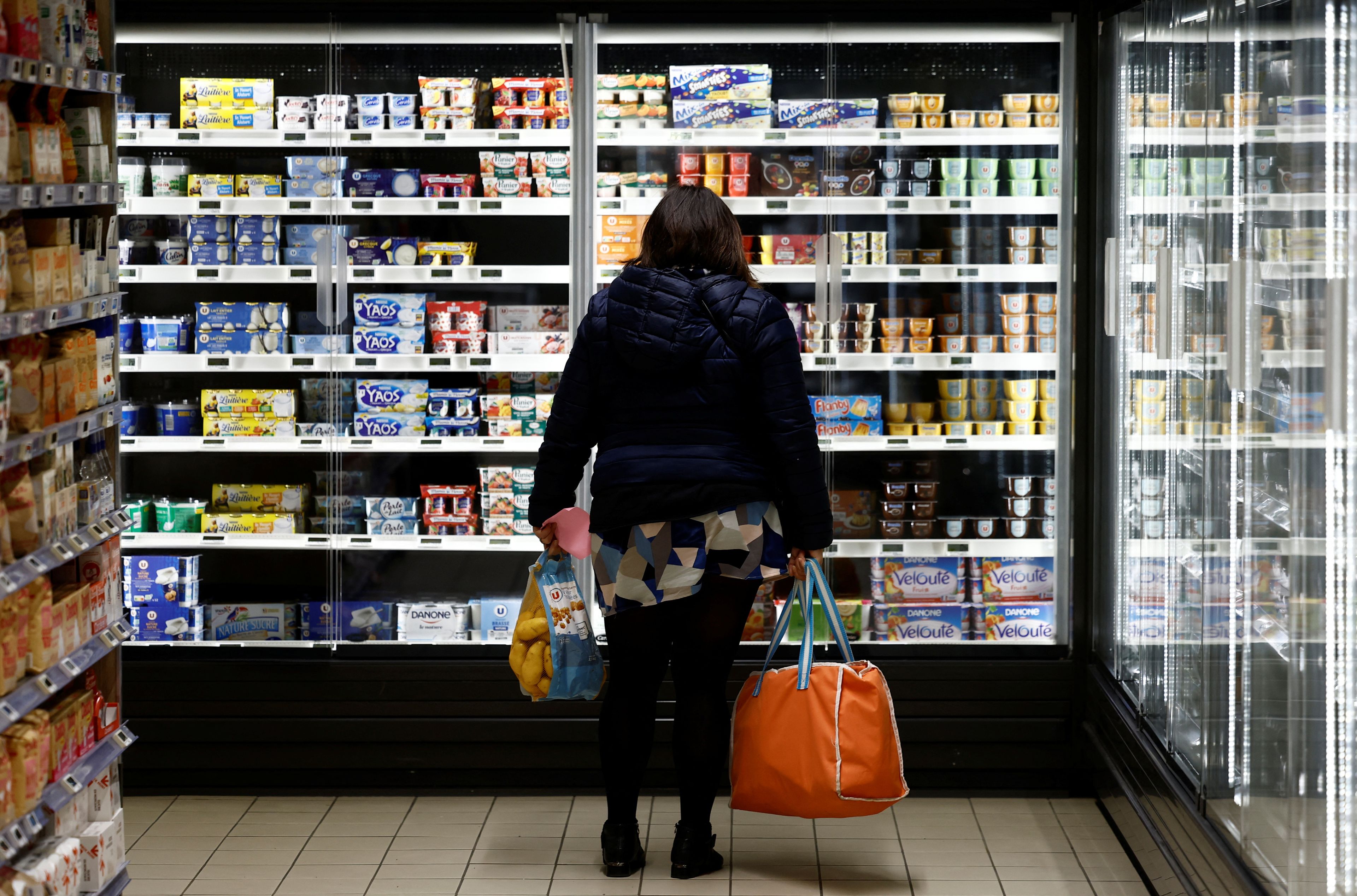 Una mujer contempla los precios de los productos lácteos mientras realiza la compra en un supermercado.