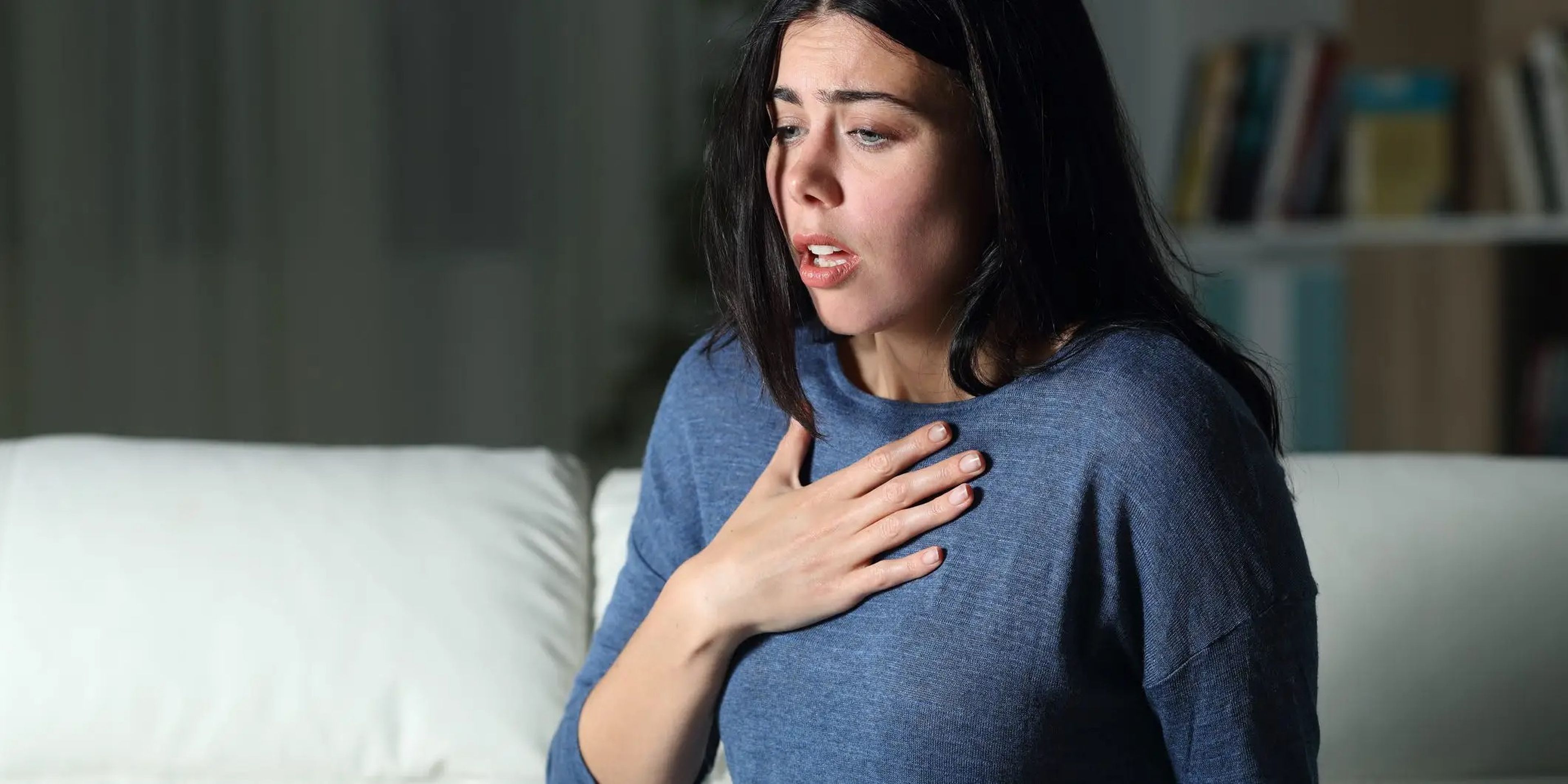 Woman with hand on chest in pain.