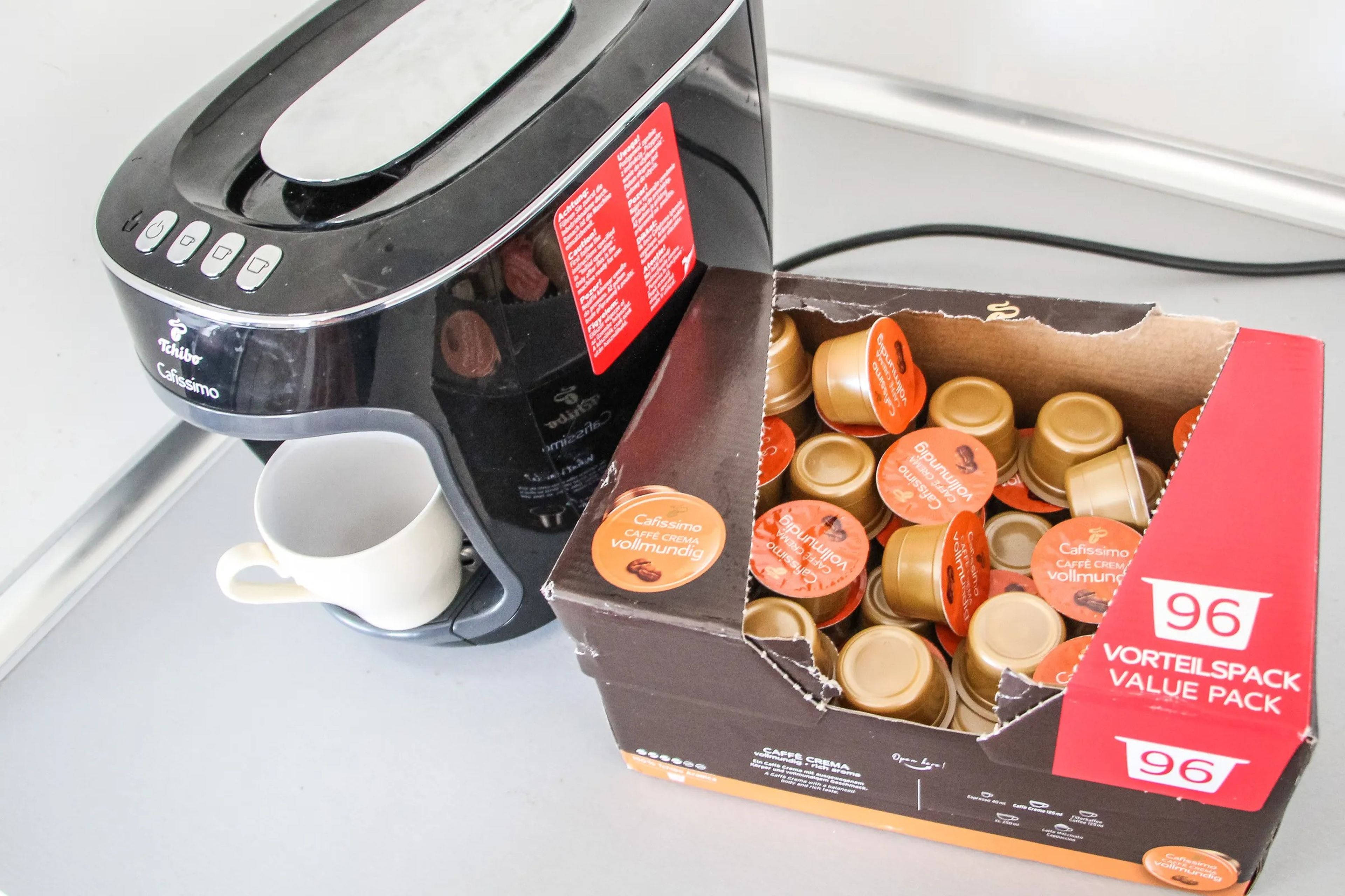 A box of single use coffee pods sits next to a coffee maker