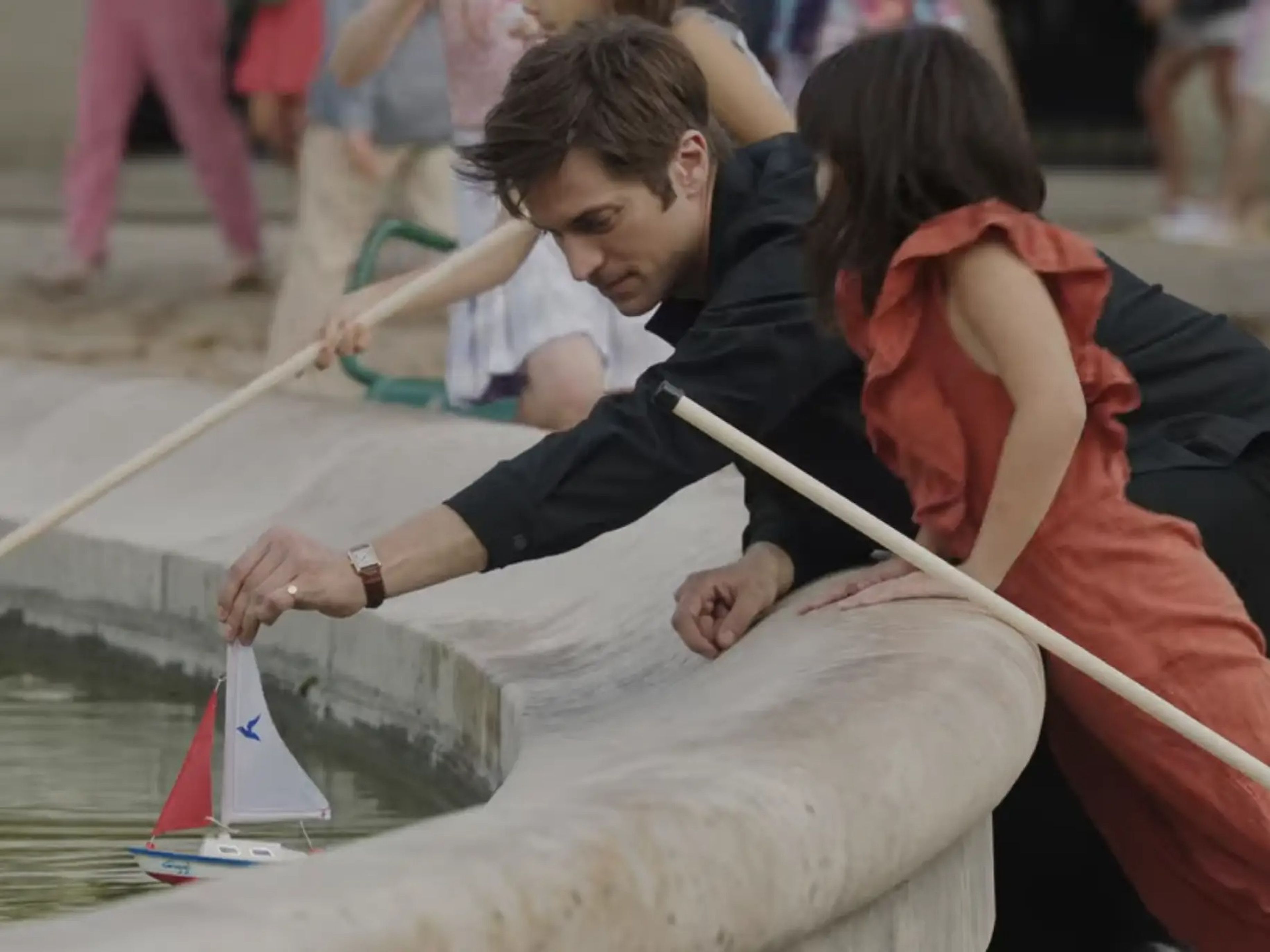 Gabriel putting a sailboat in a fountain for a young girl on emily in paris season three episode nine