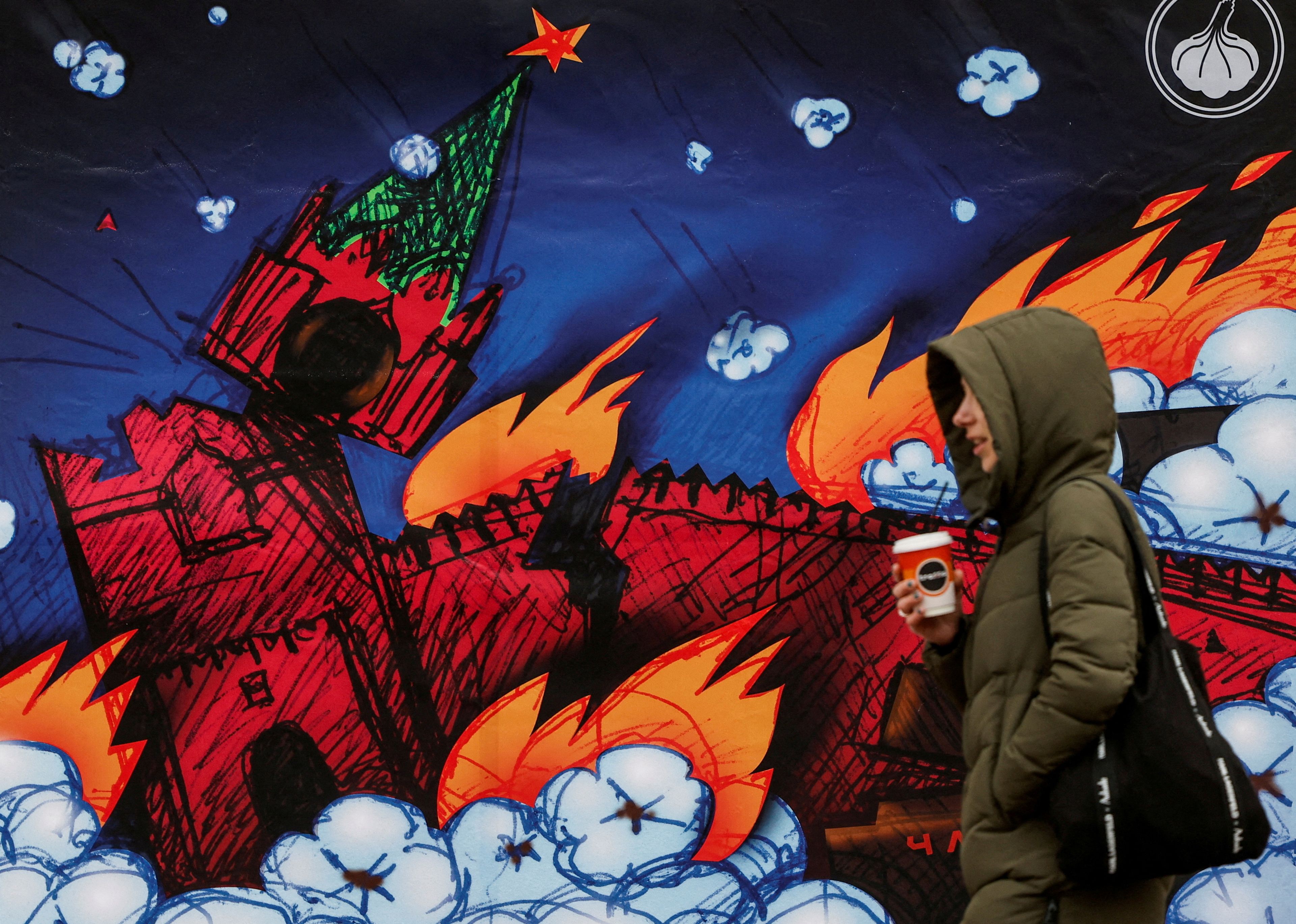 Una mujer pasea en Kiev junto a una gigantesca reproducción de un sello postal que representa la quema del Kremlin.
